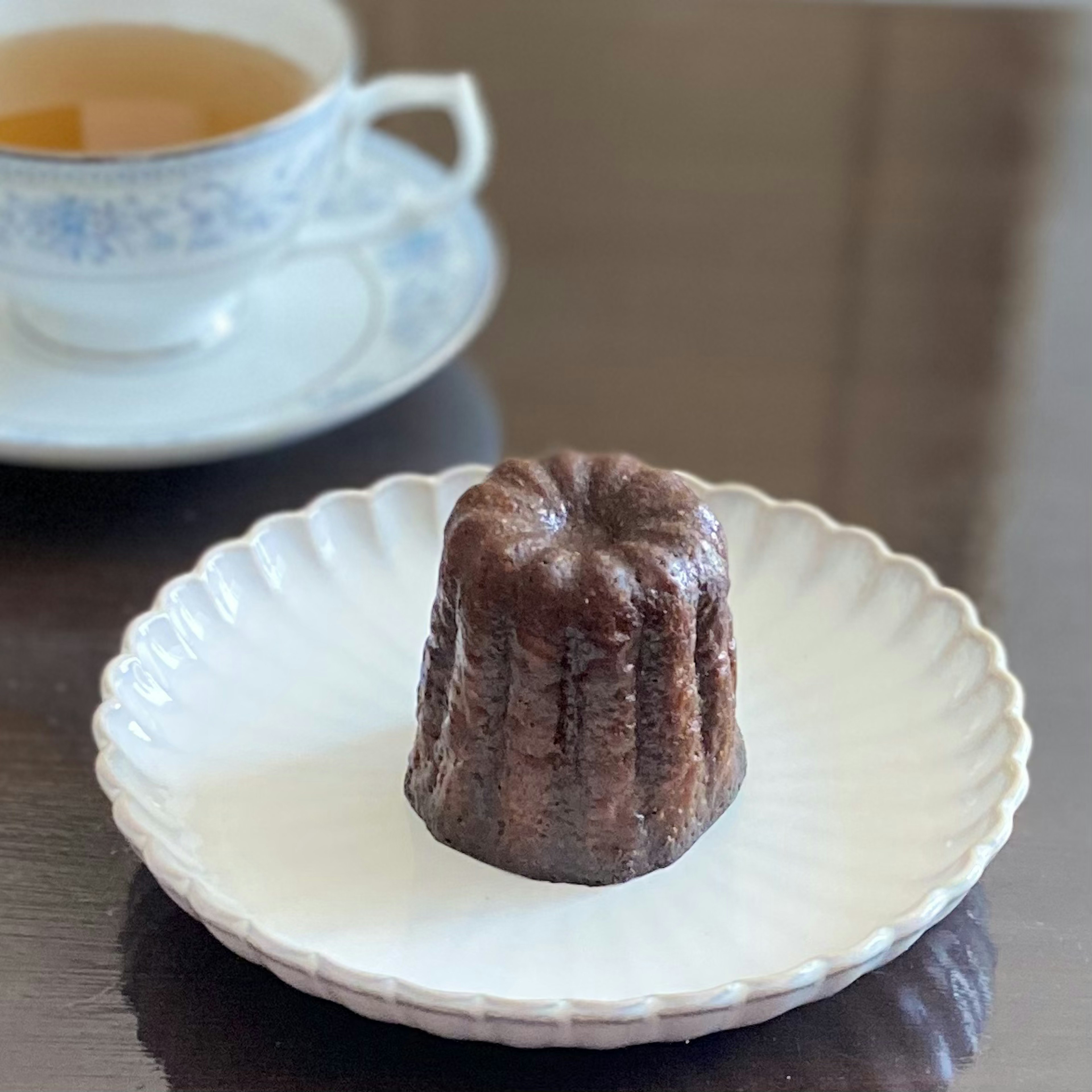 Canelé trên đĩa trắng với tách trà ở phía sau