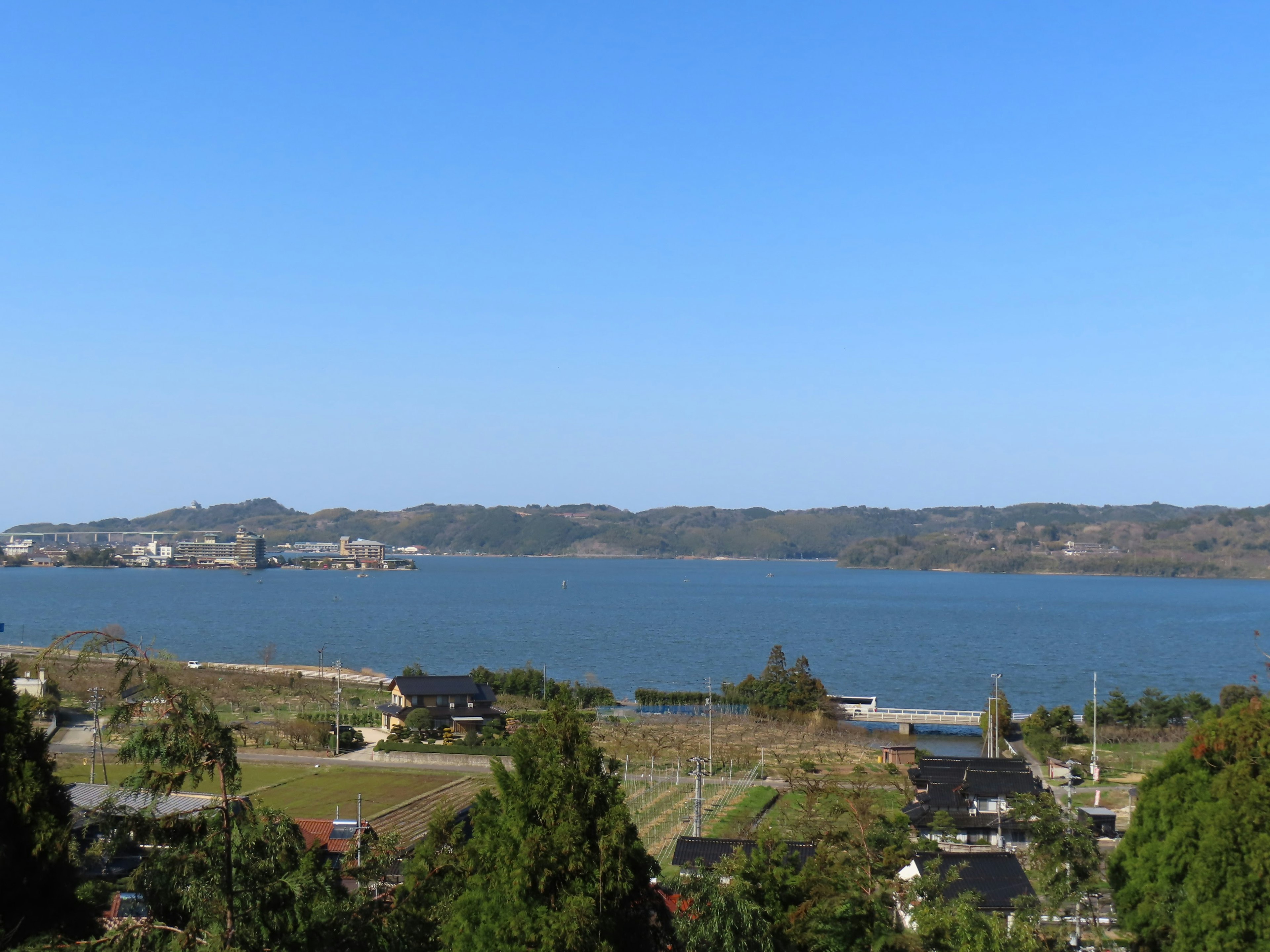 Vue panoramique d'un ciel bleu et d'une mer calme avec des maisons et des arbres verts à proximité