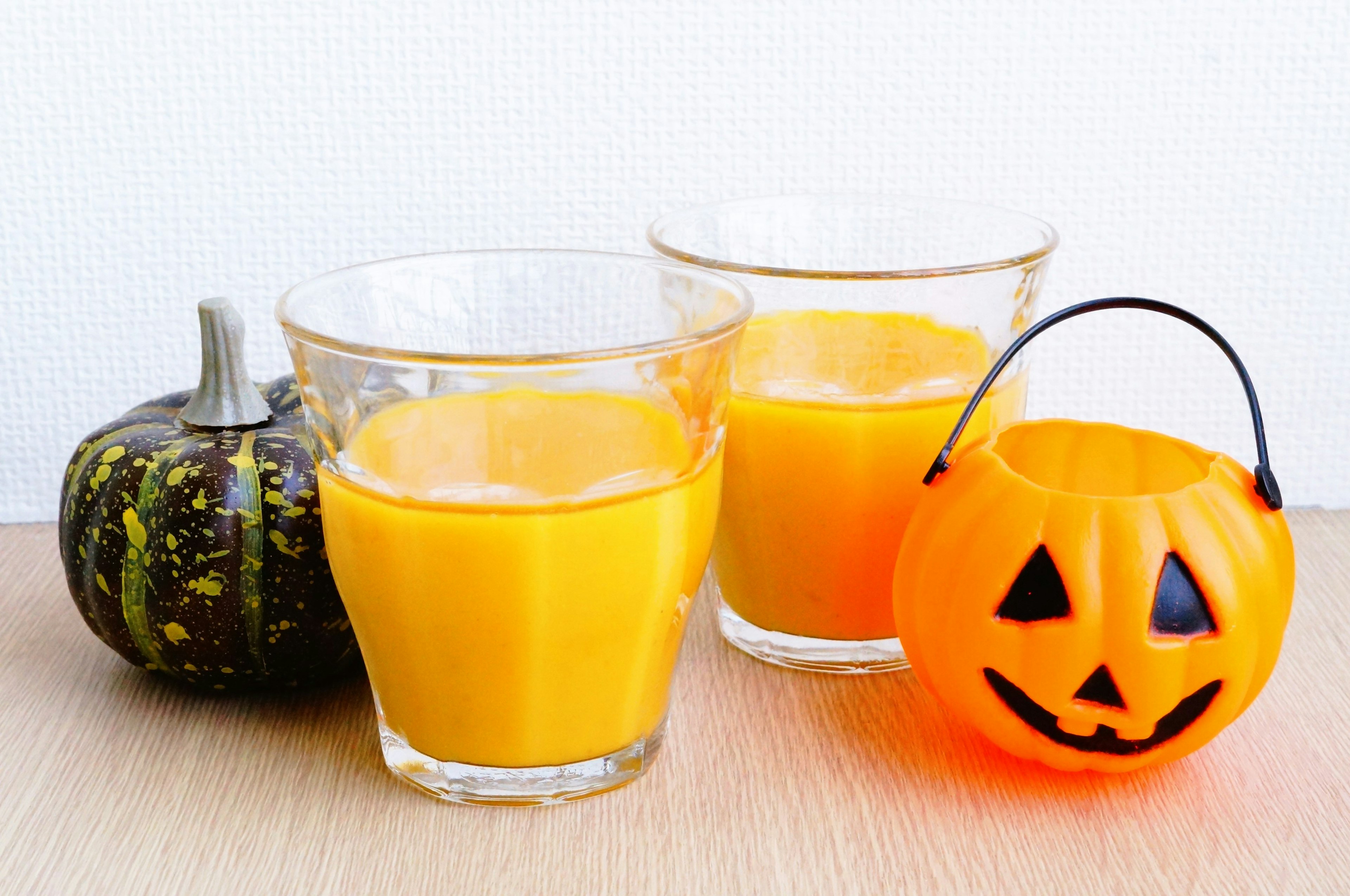 Dos vasos de jugo de naranja junto a una calabaza de Halloween y un farolillo de calabaza