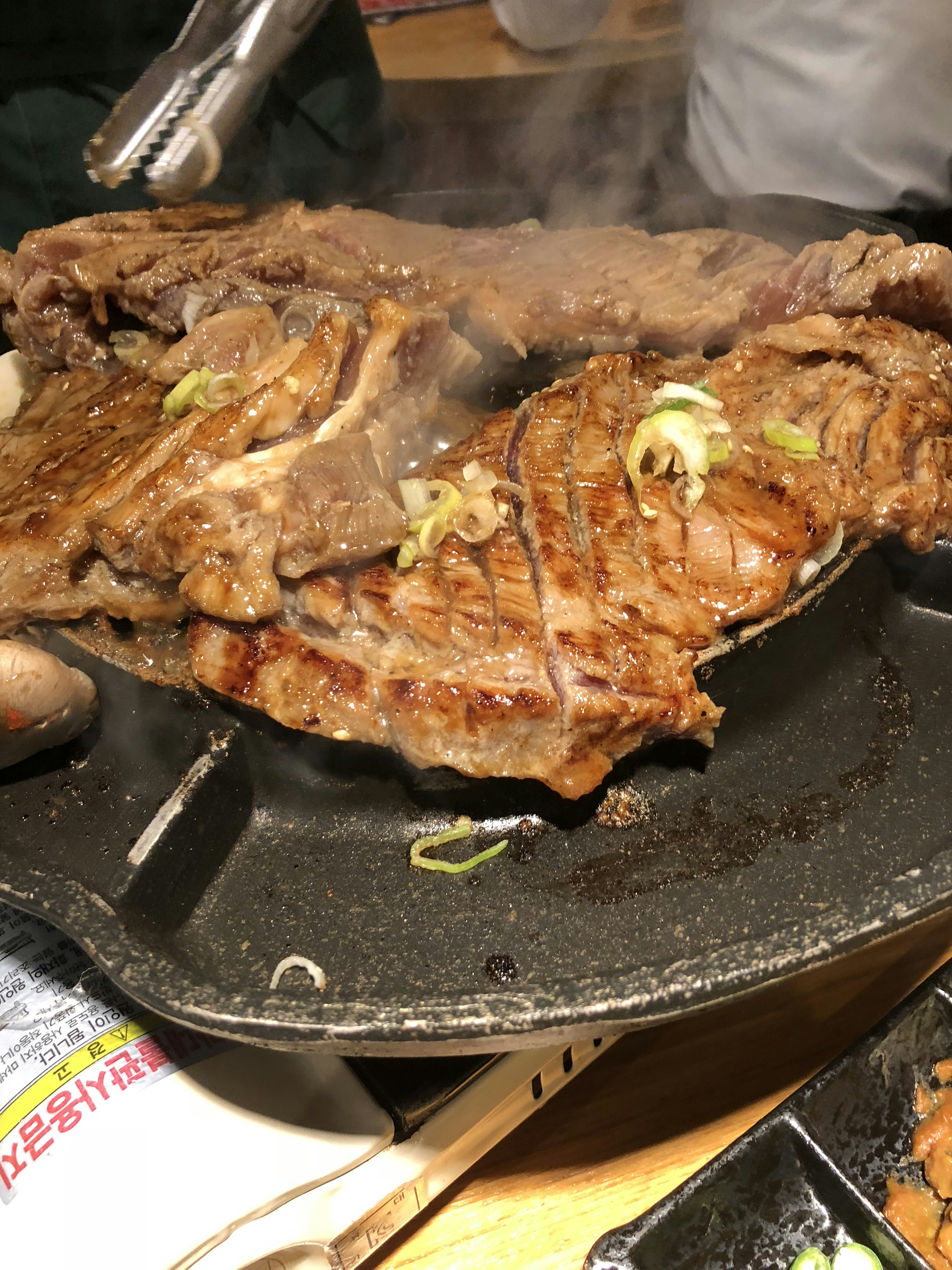 Juicy meat sizzling on a hot iron plate with aromatic green onions