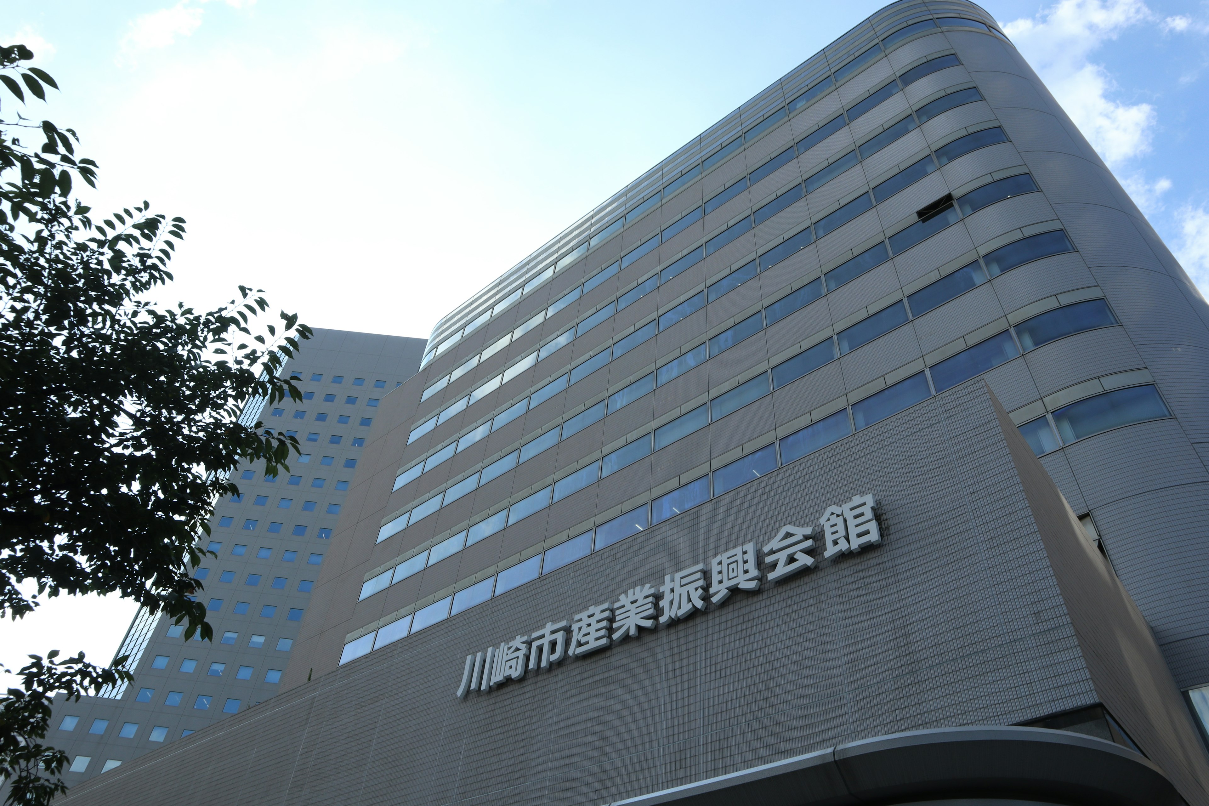 Close-up of Kawasaki City Industrial Promotion Hall featuring modern architecture and blue sky