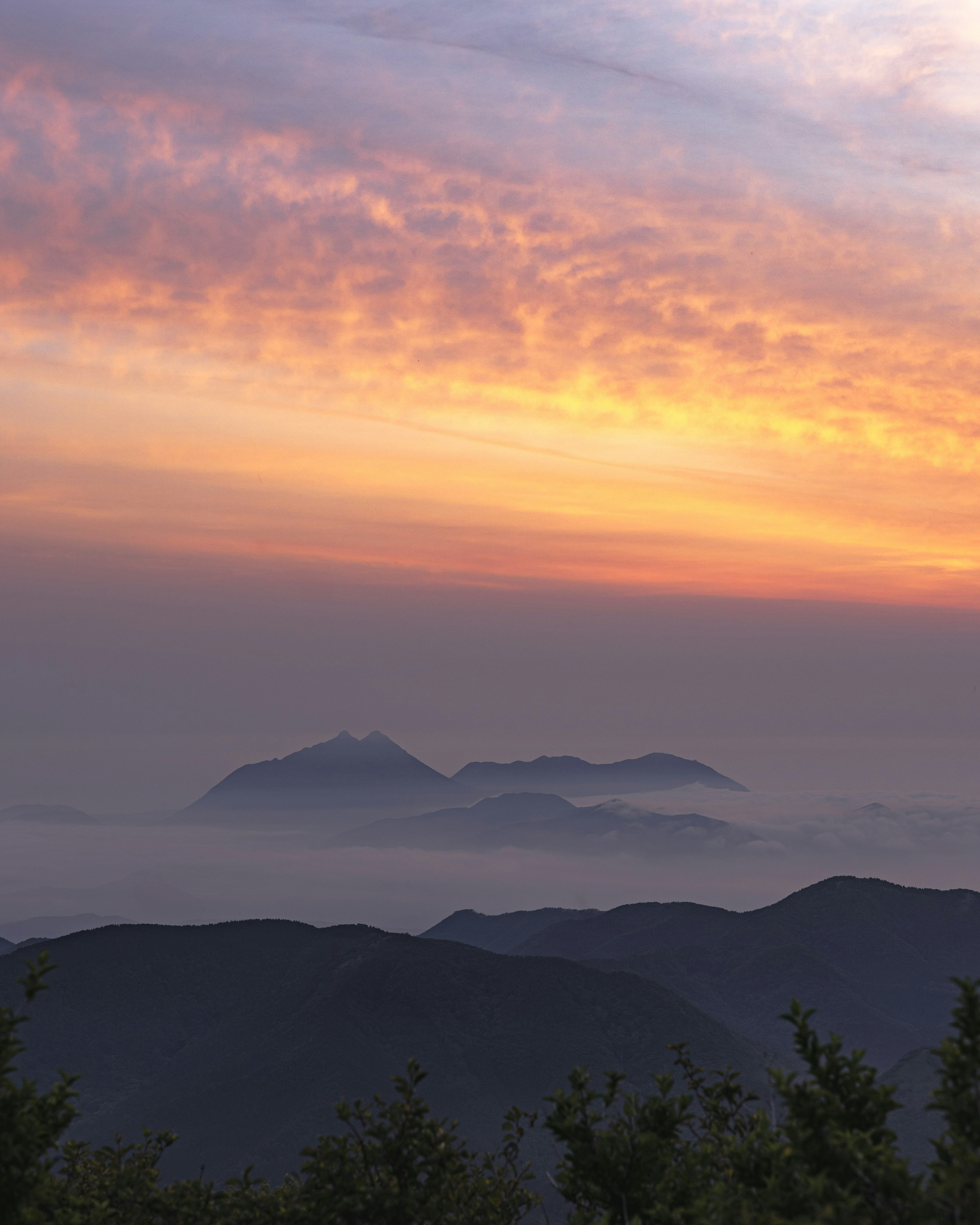 Berglandschaft mit lebhaftem Sonnenuntergang und nebligen Wolken