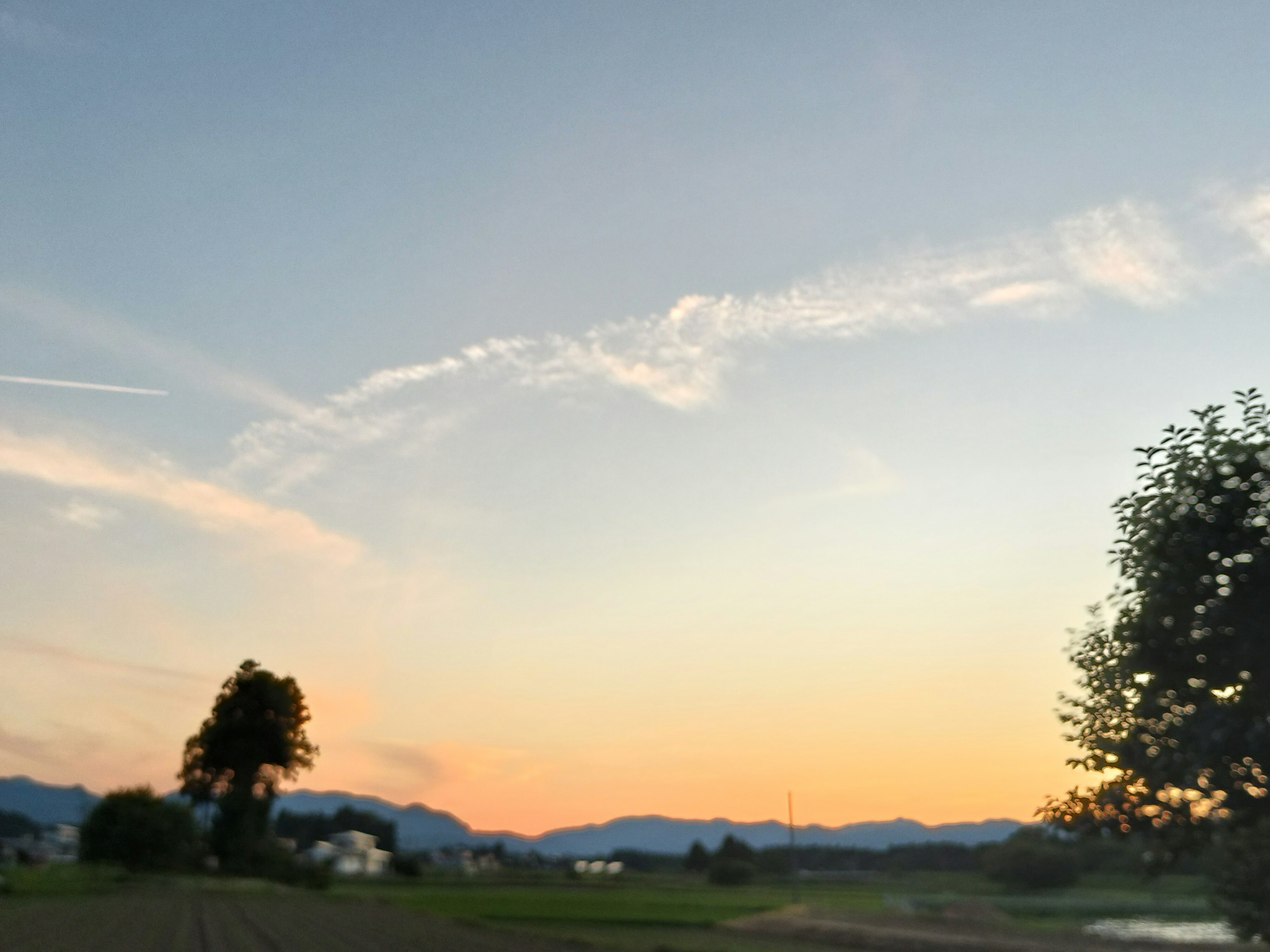 Ciel au coucher du soleil avec des montagnes et de la verdure comprenant des arbres et des maisons