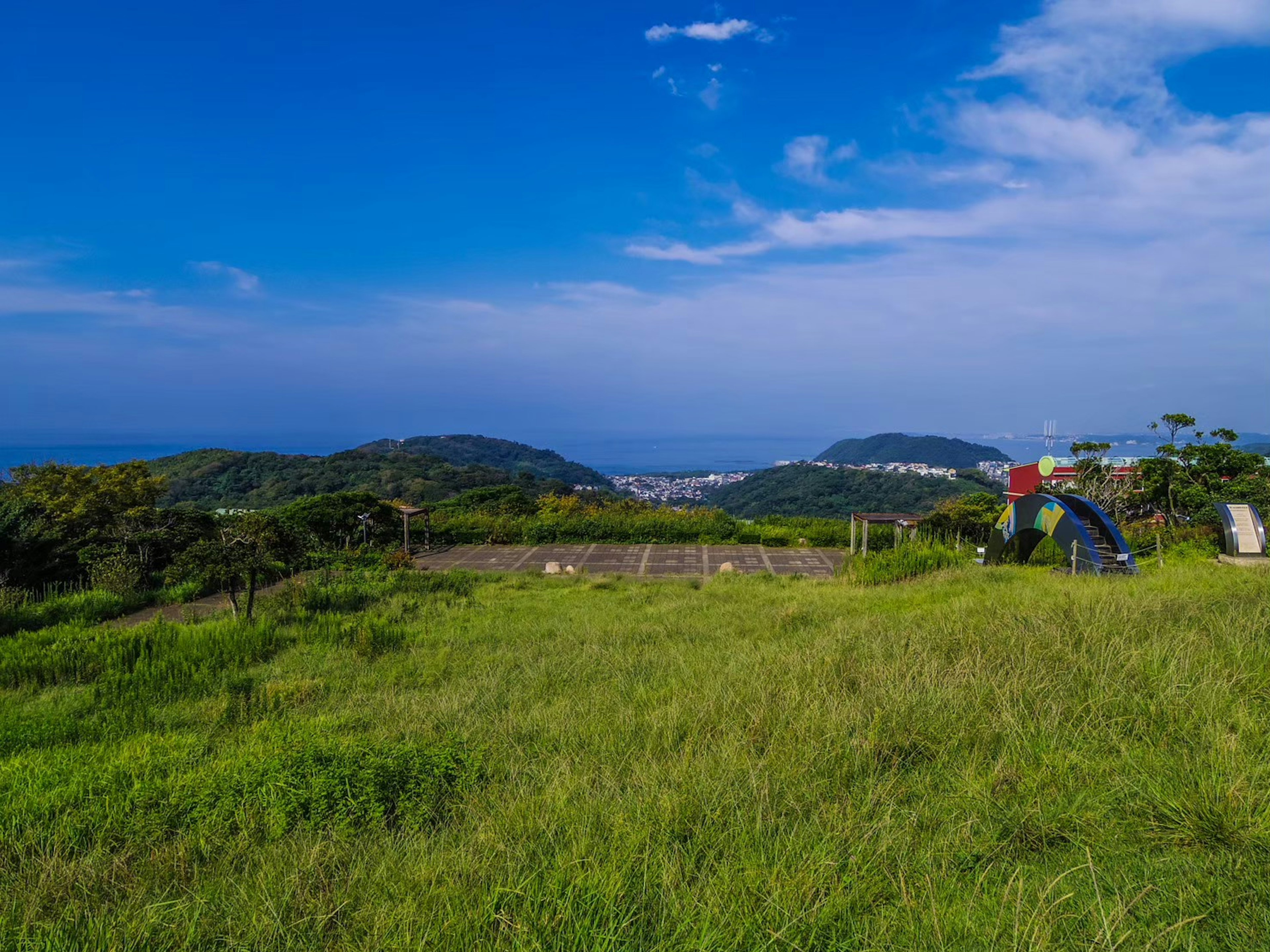 青い空と緑の草原が広がる風景に人物がいる