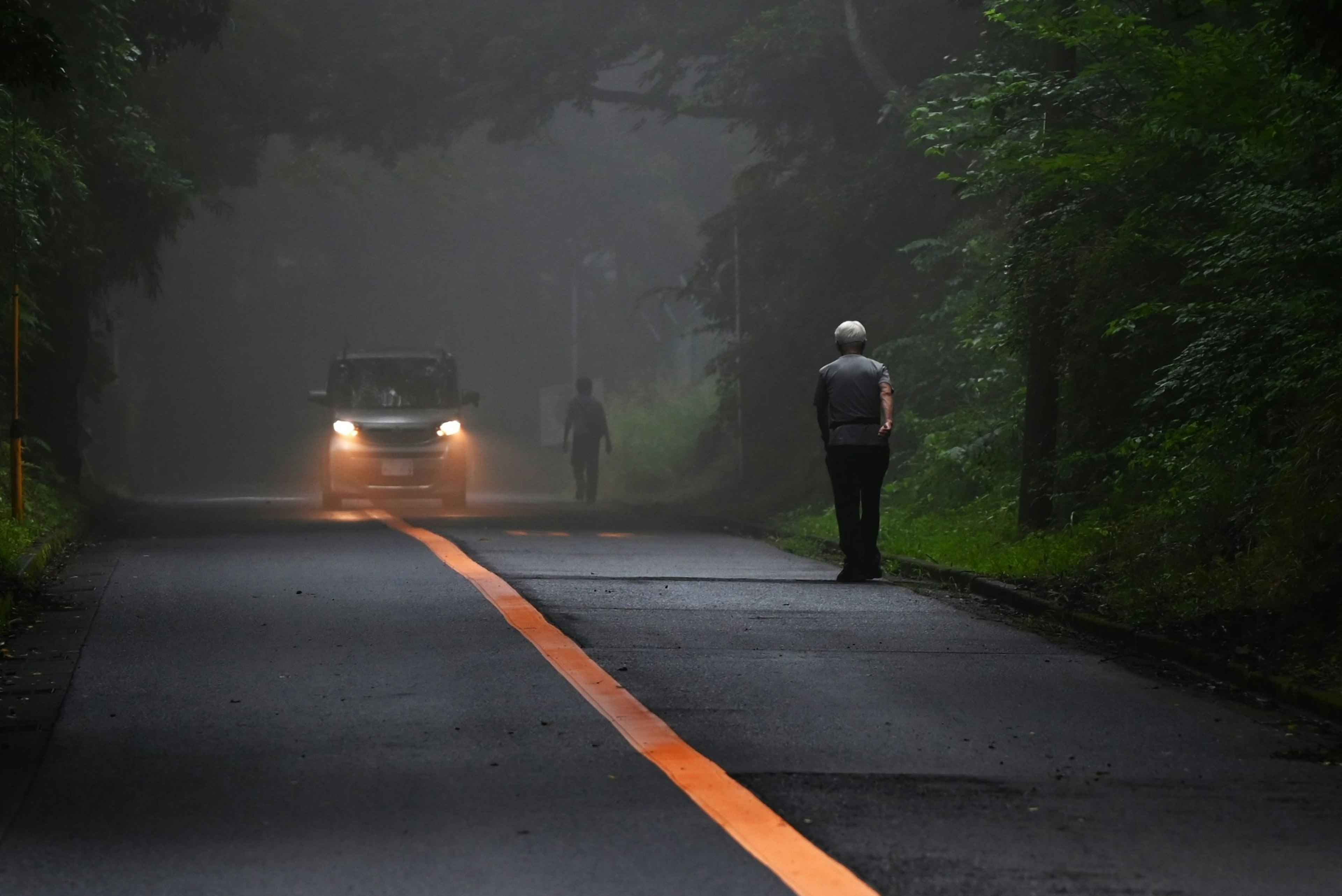 Scène d'une route dans le brouillard avec une voiture et une personne