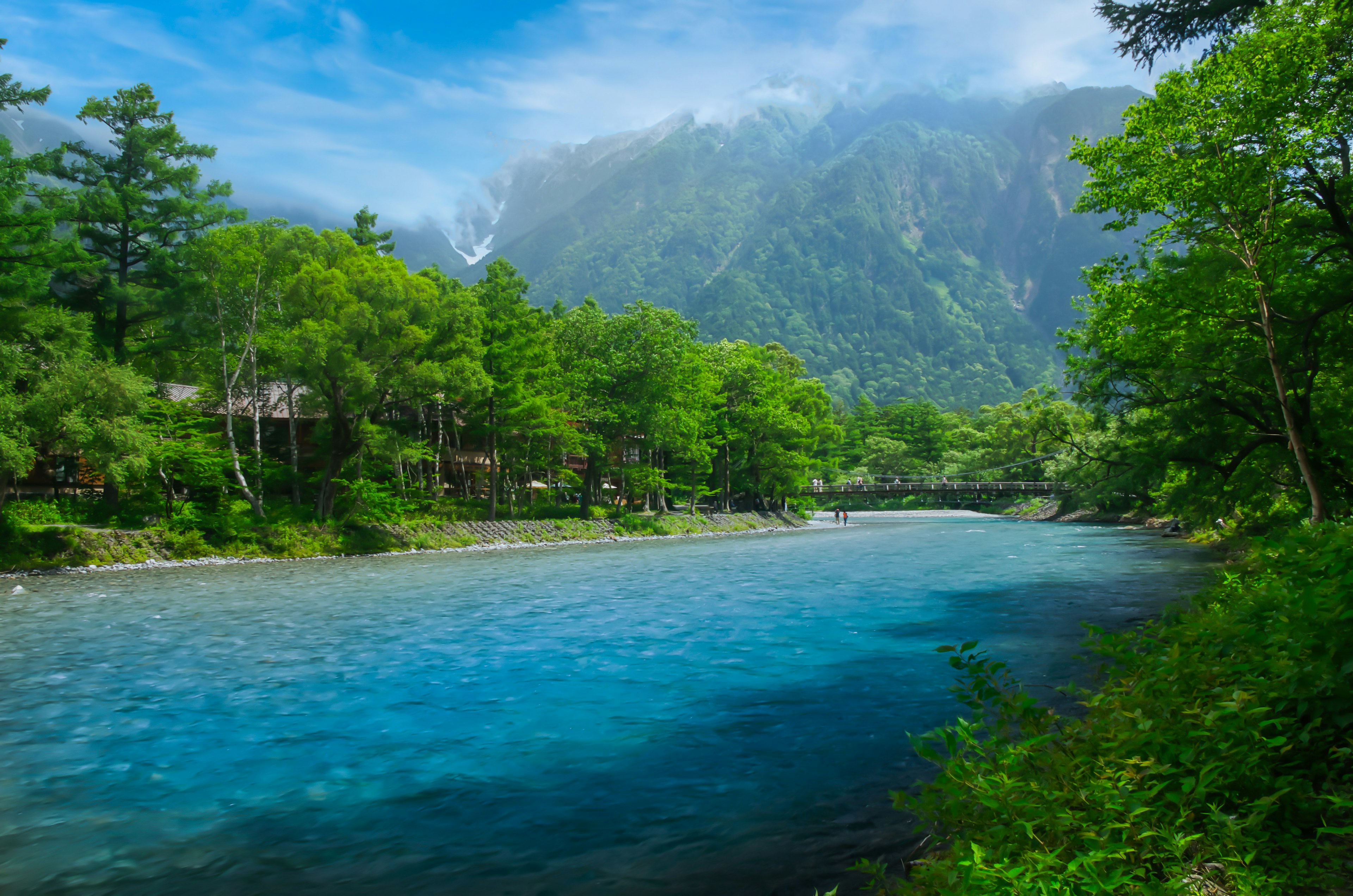 Vue pittoresque d'une rivière bleue entourée d'arbres verts luxuriants et de montagnes