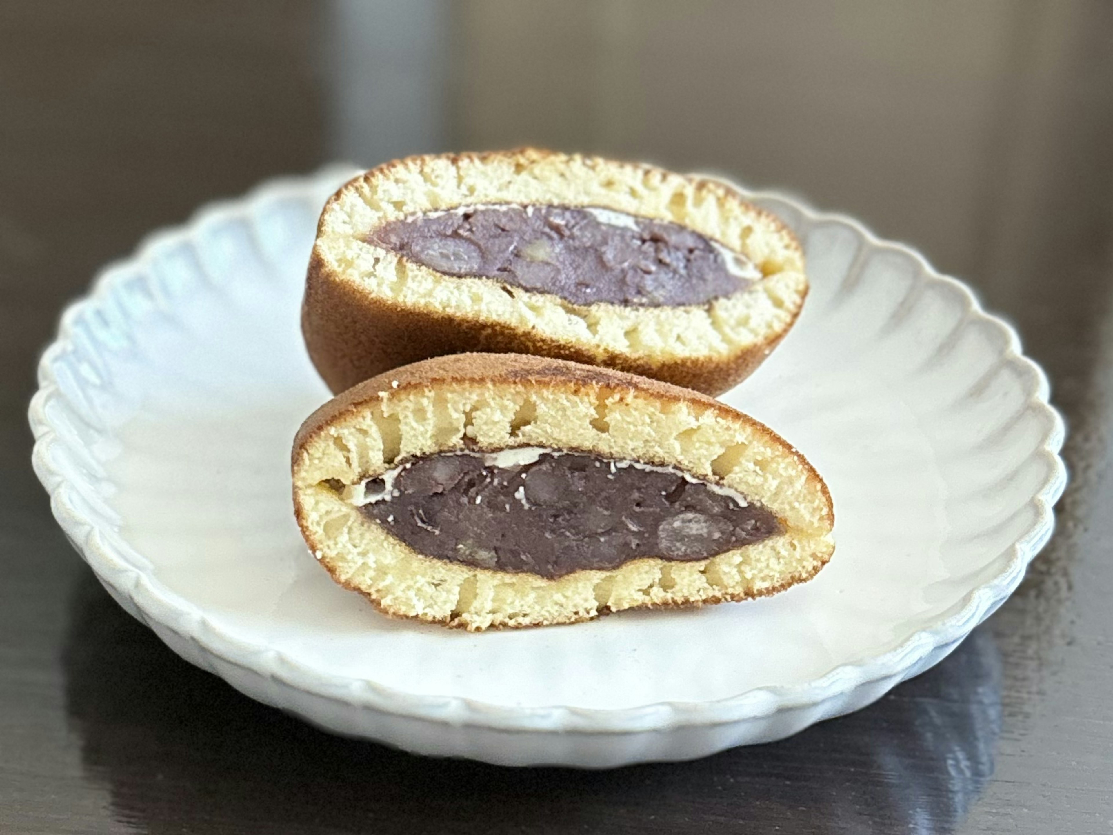 白い皿に盛られた半分にカットされたお菓子の画像 中には紫色のあんこが見える