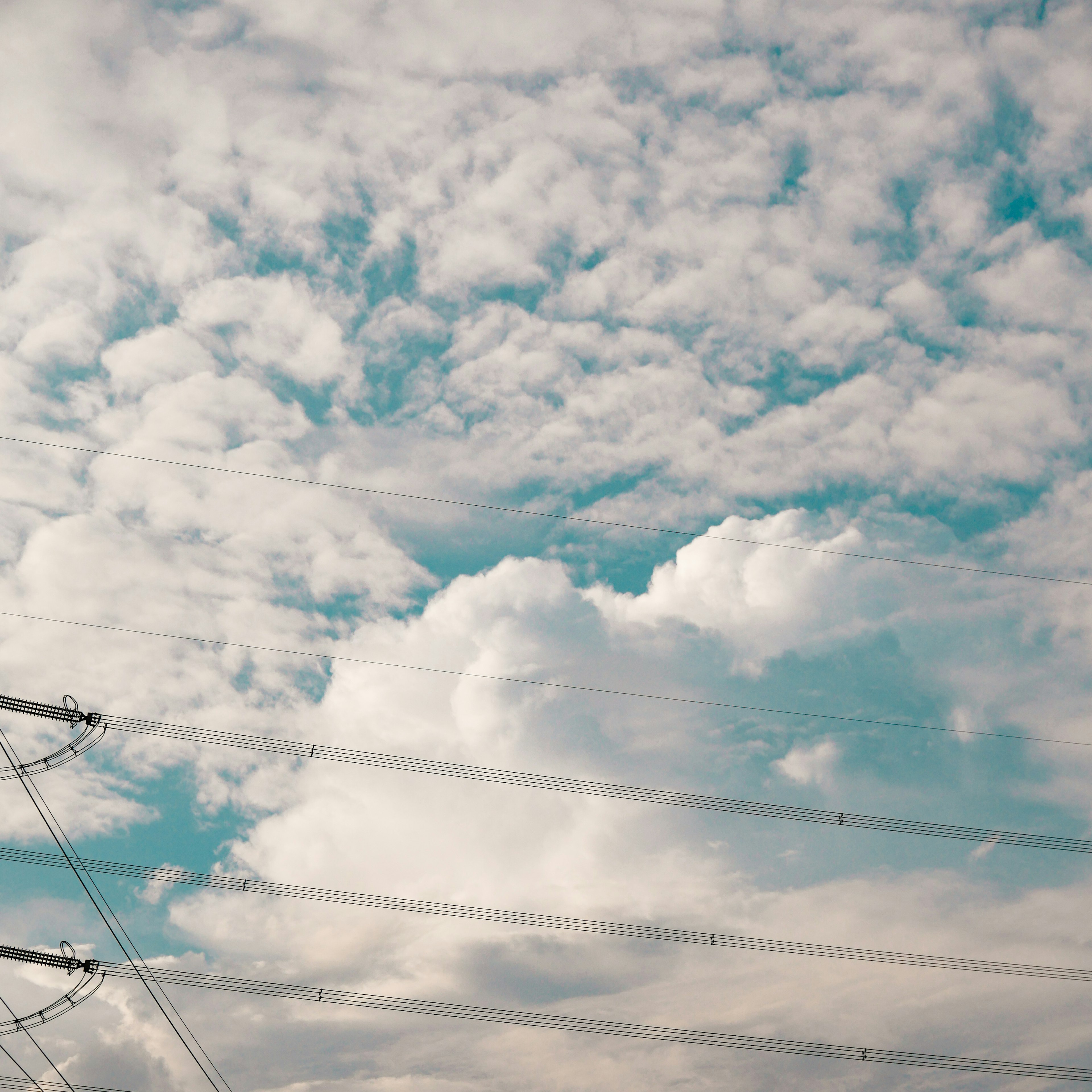 Langit biru dengan awan putih dan garis listrik yang terlihat