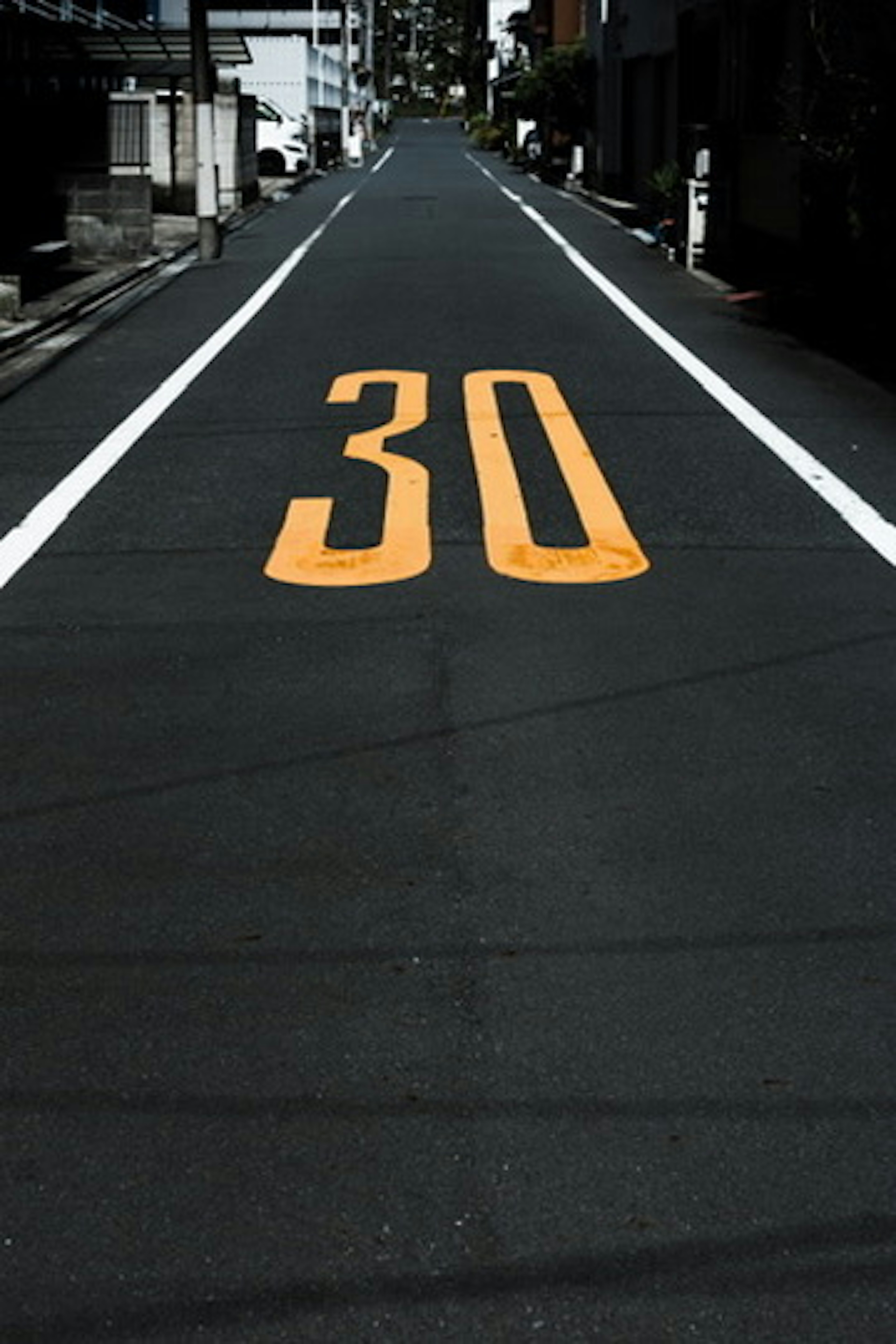 Orange number 30 painted on a dark road