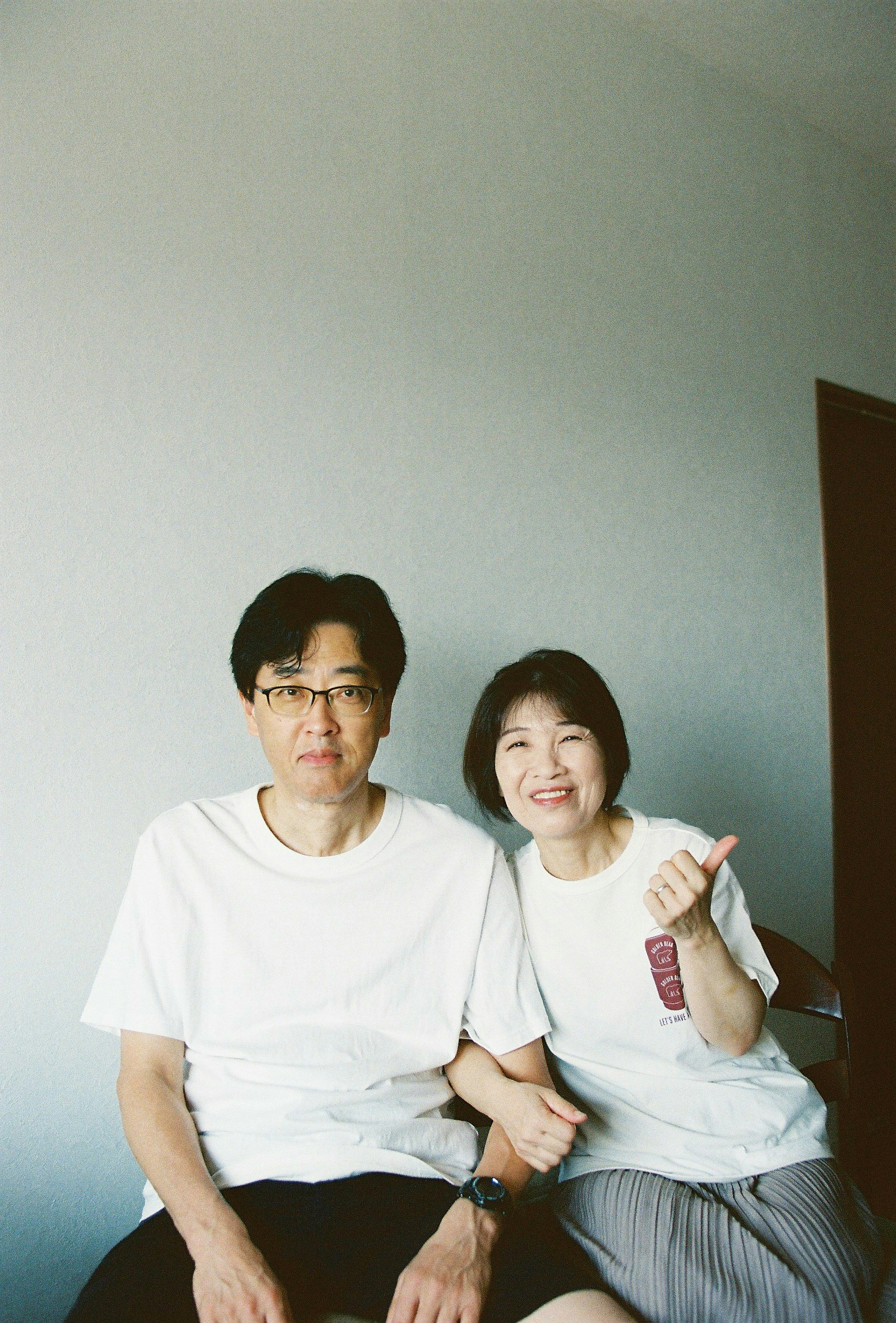 Man and woman sitting on a sofa wearing white t-shirts