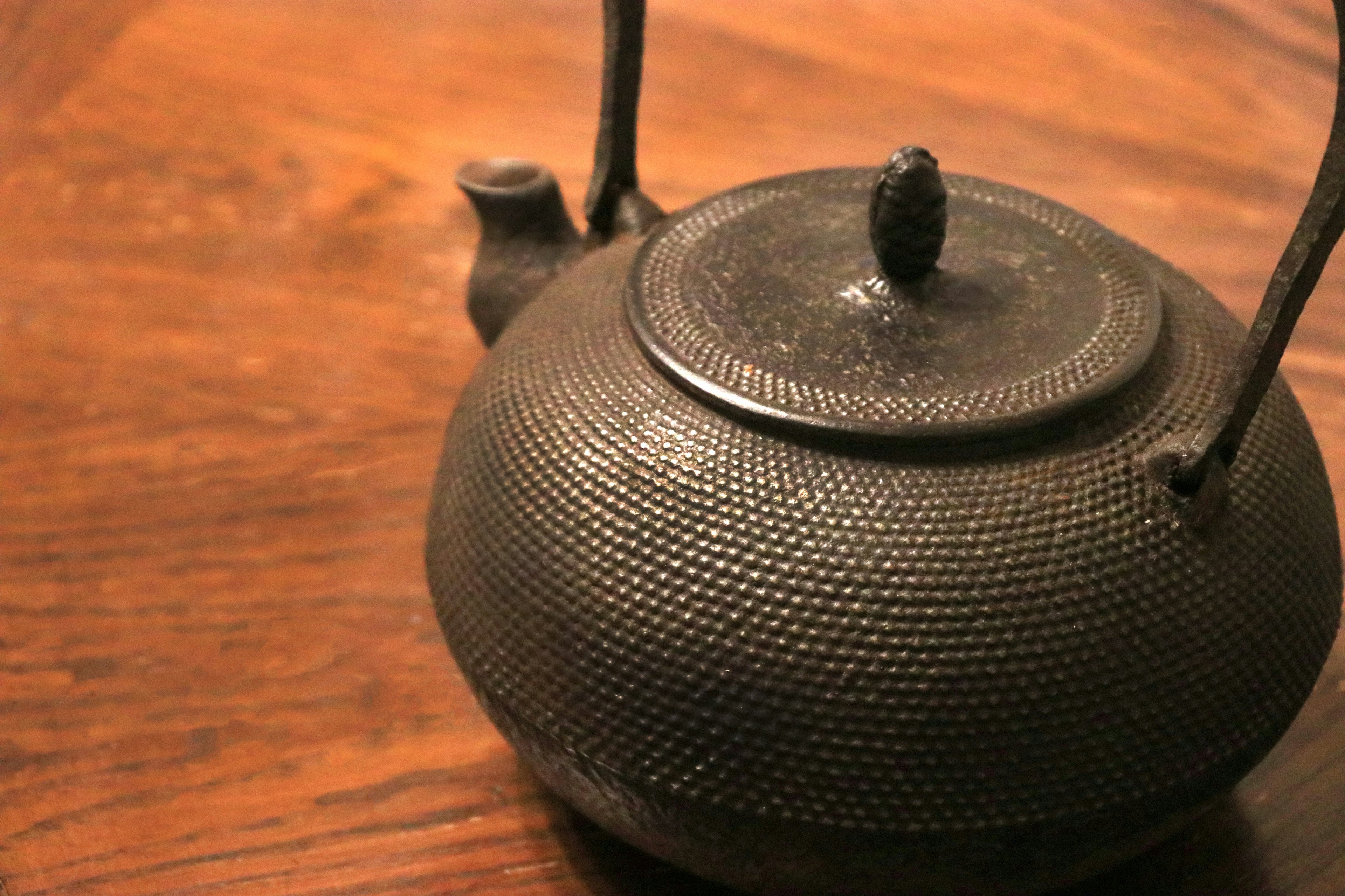 A black iron teapot placed on a wooden table