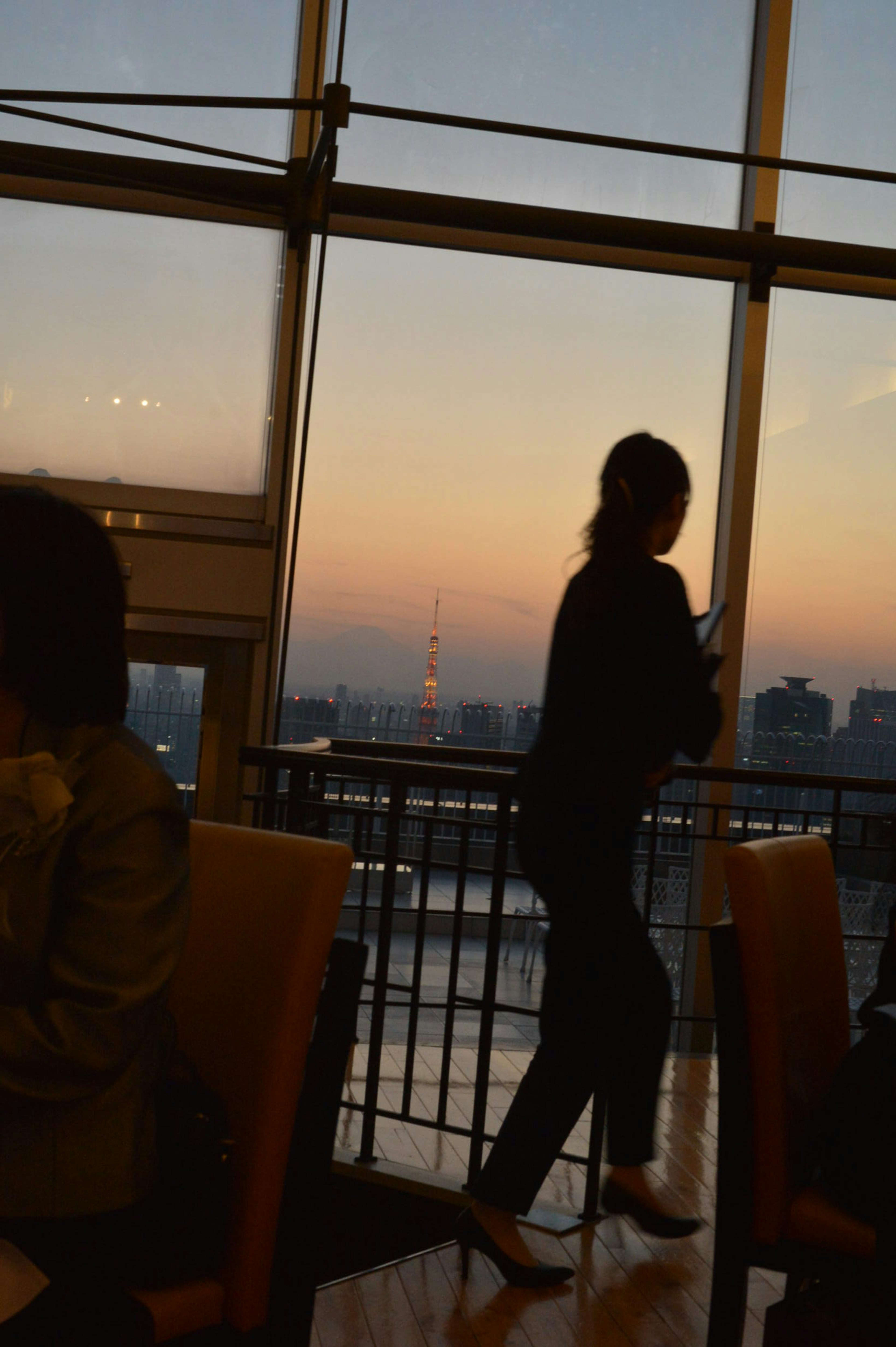 Silhouette einer Frau, die gegen einen Sonnenuntergang mit Stadtansicht geht