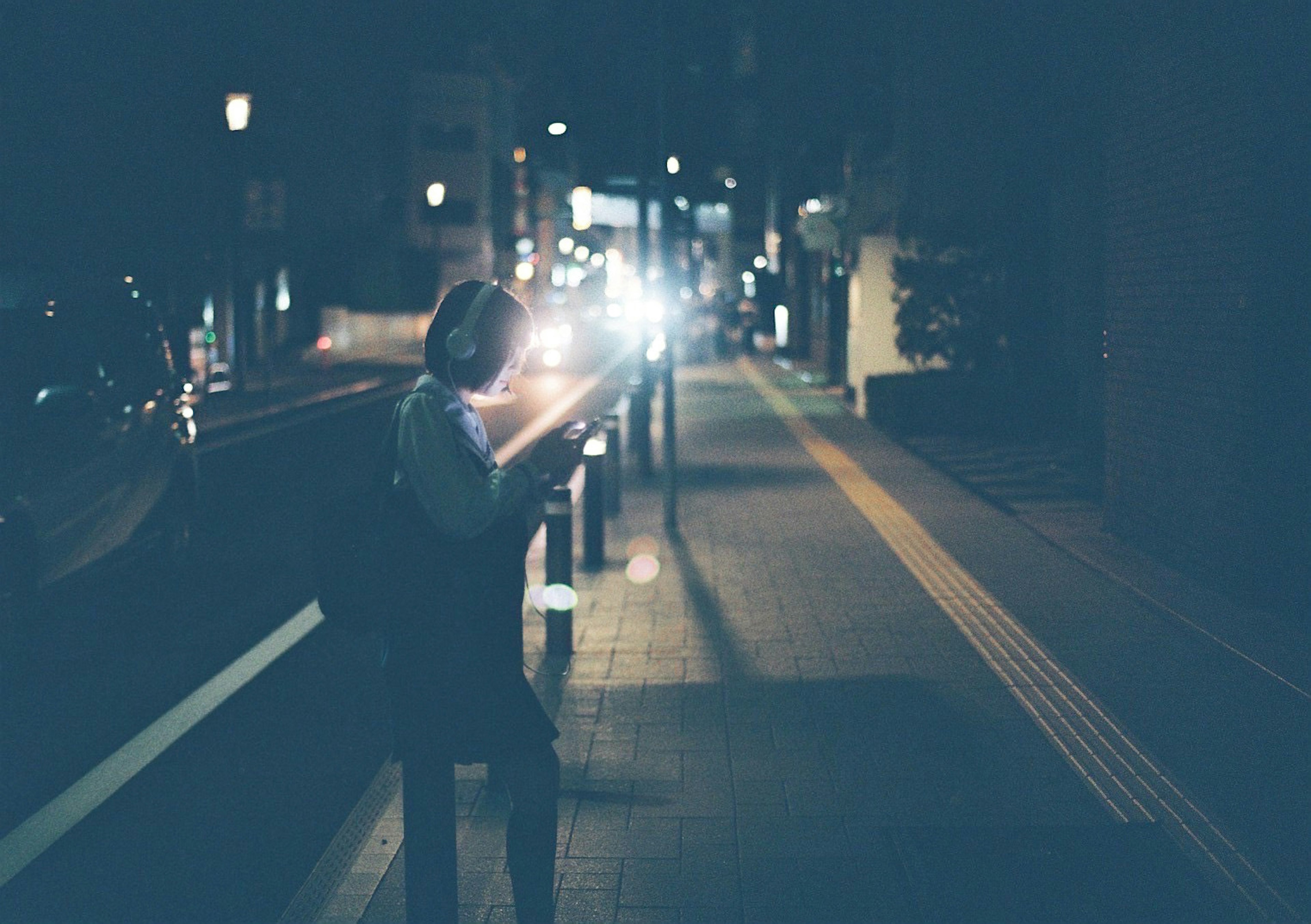 Person walking in a nighttime urban setting with light effects