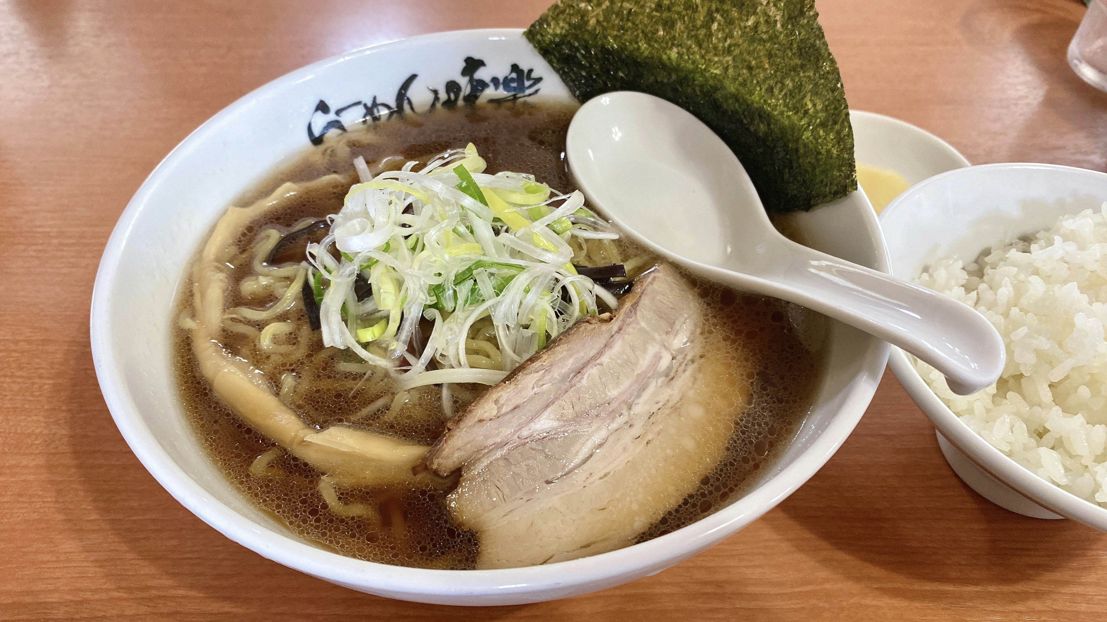 ラーメンのボウルに細切りのネギとチャーシューがのっている