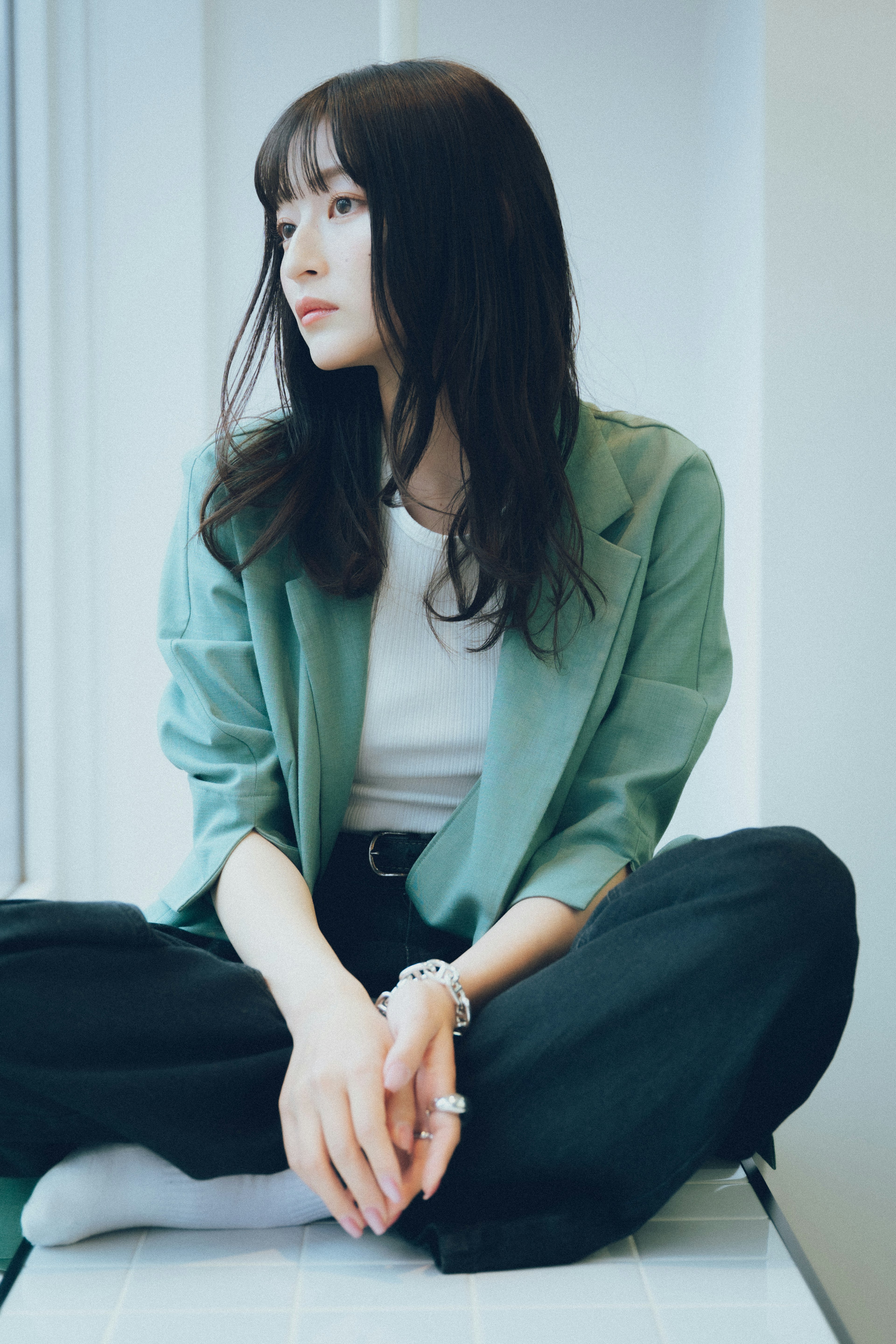 Una mujer con una chaqueta verde sentada junto a una ventana