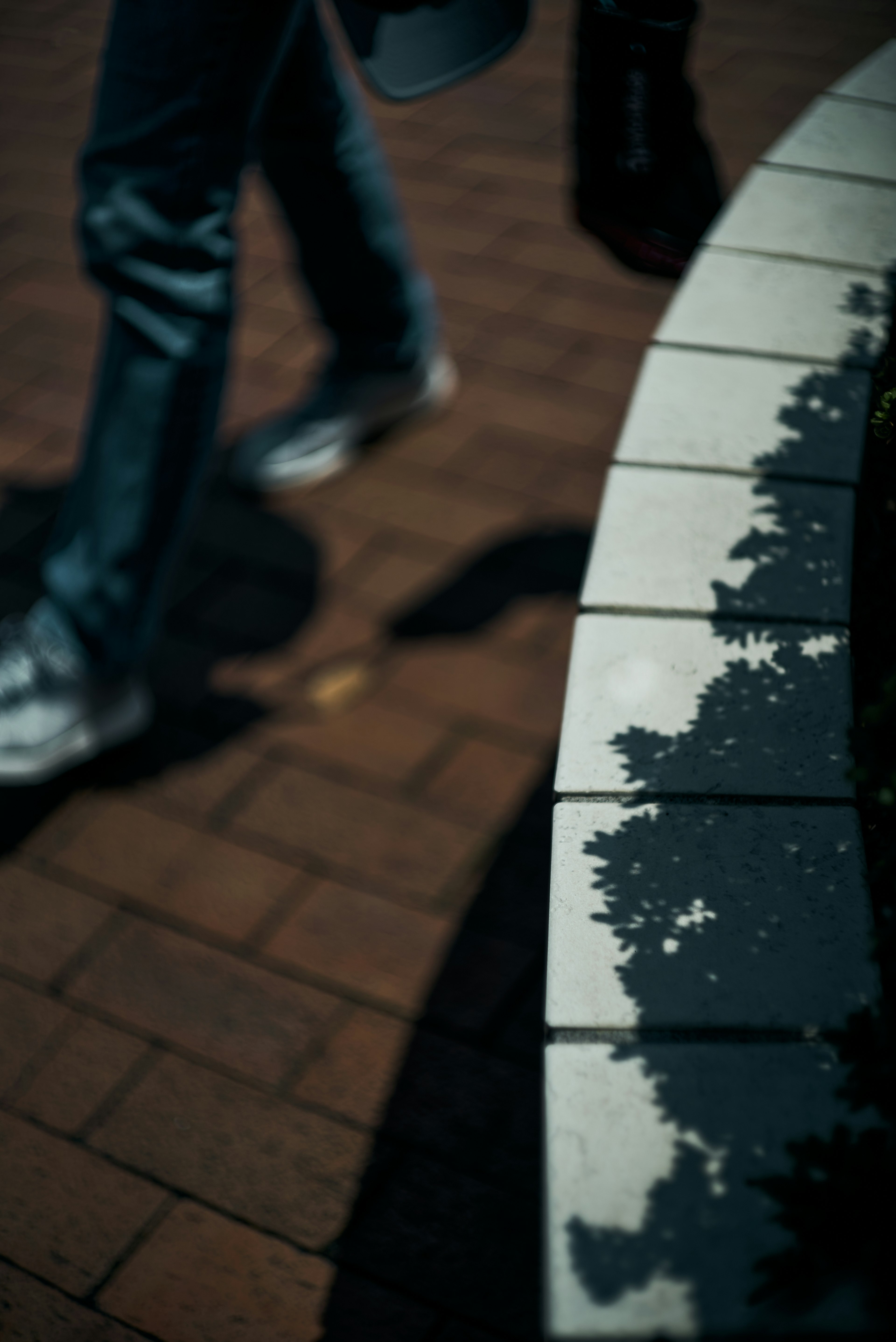 Una persona caminando con sombras en un borde de piedra curvo