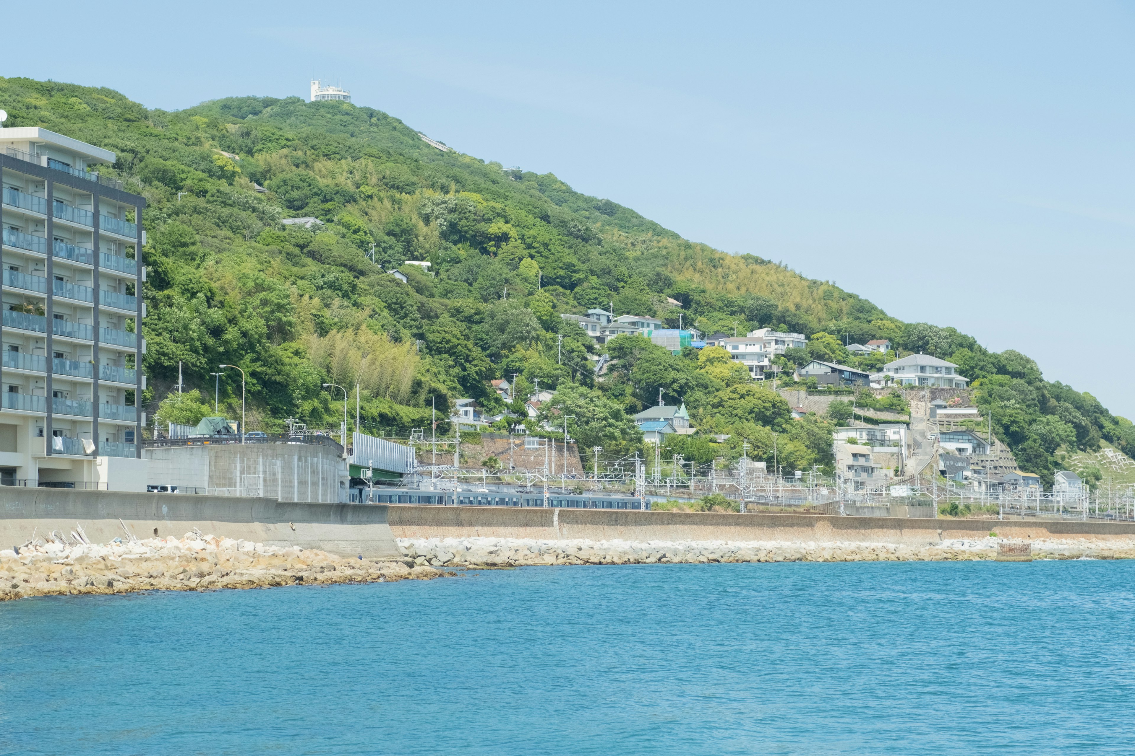 沿着海岸线的建筑与蓝色海水和绿色山丘