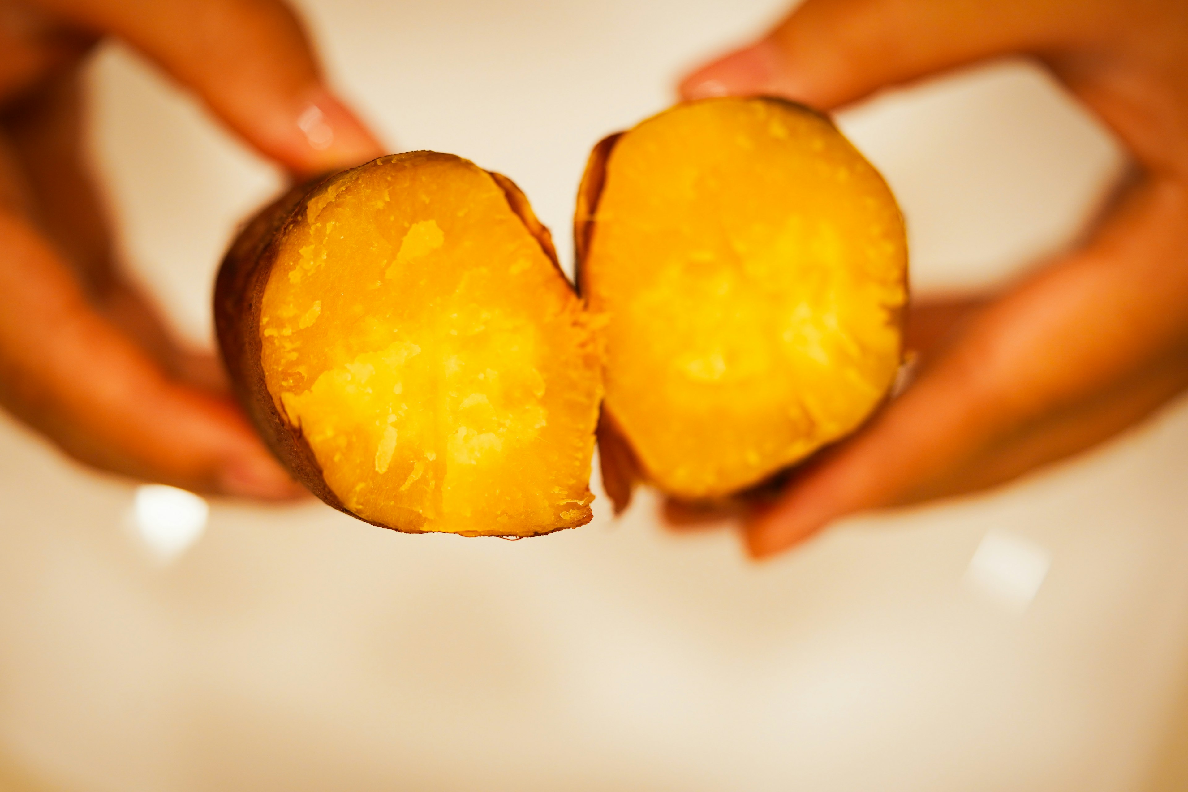 Photo of a sweet potato cut in half held in hands