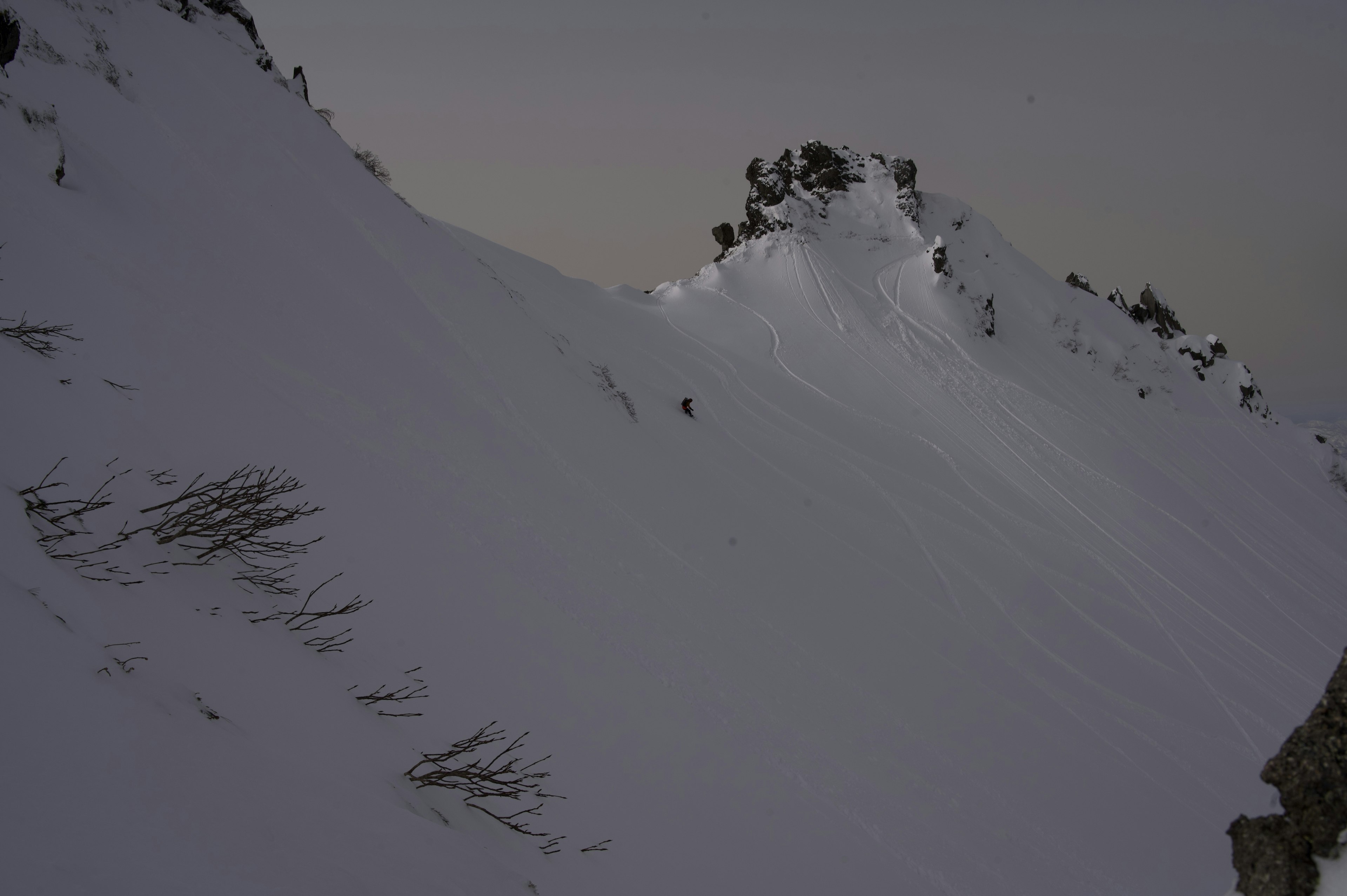 Pendiente de montaña cubierta de nieve con un pico rocoso puntiagudo