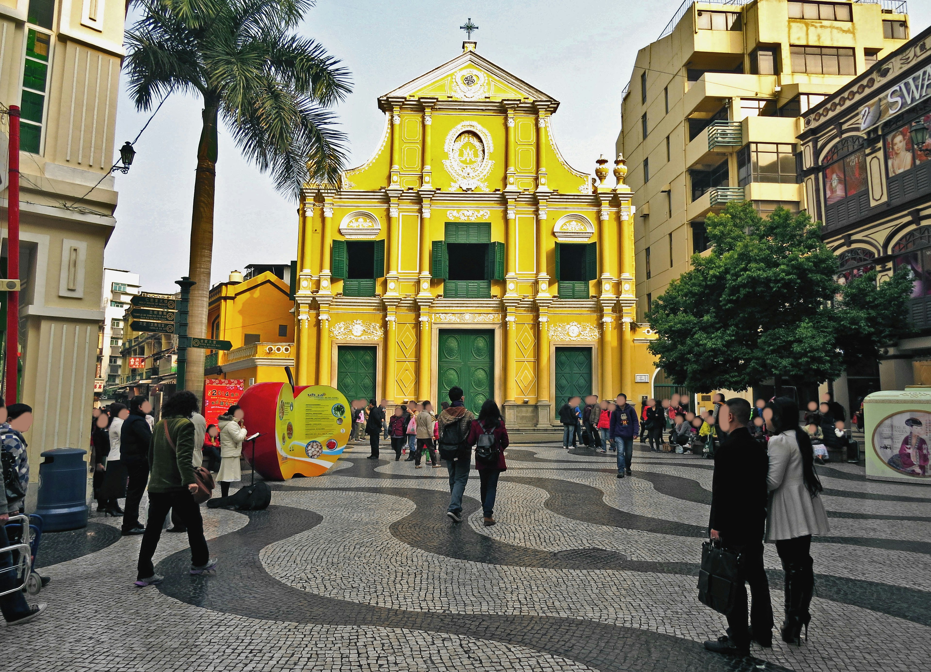 Personas reunidas en una plaza con una iglesia amarilla al fondo