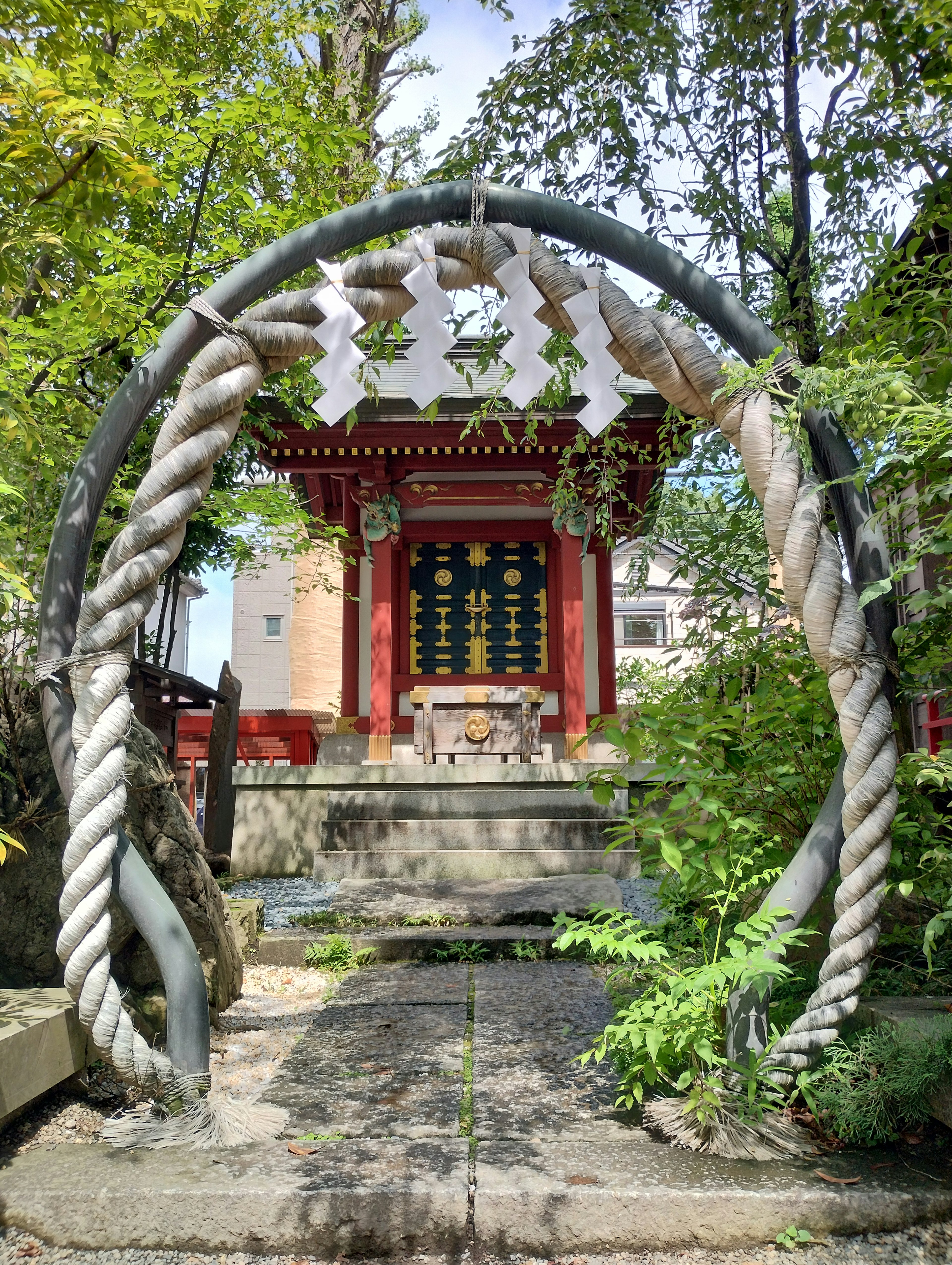 Large straw ornament at the entrance of a shrine with lush greenery