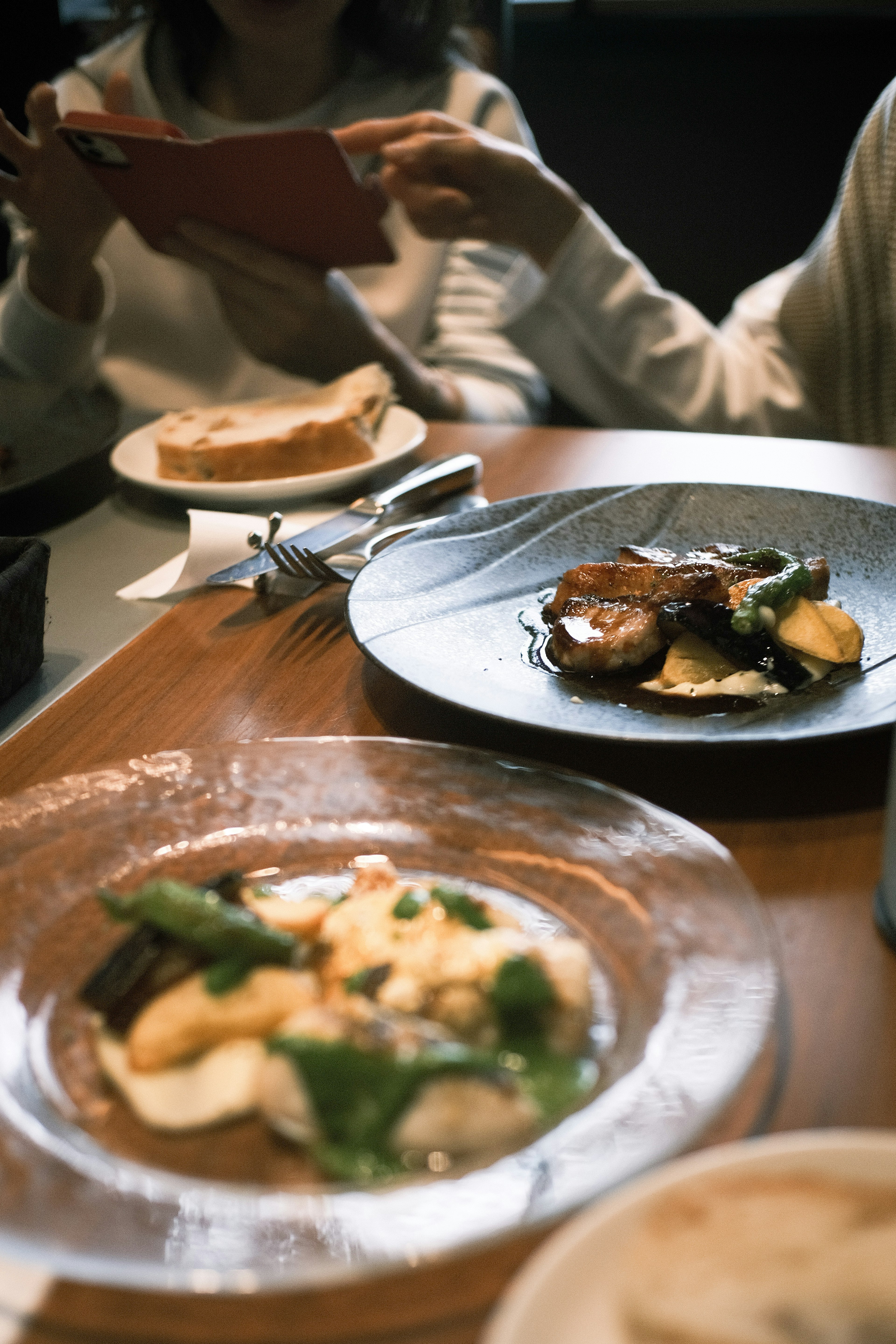 Plates of beautifully presented dishes on a table with people enjoying their meal in the background