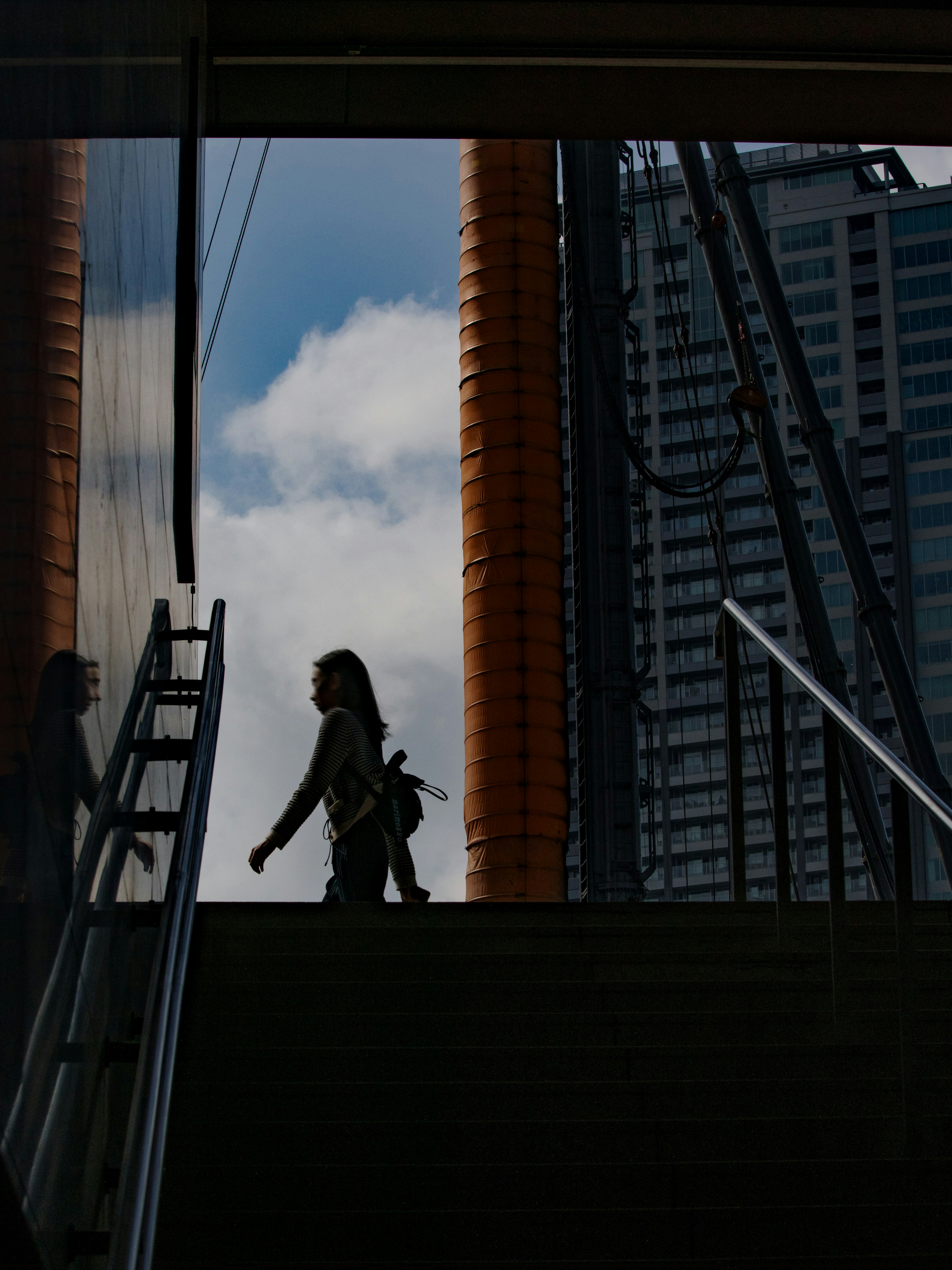 Silhouette di una donna che sale le scale con un edificio cittadino sullo sfondo