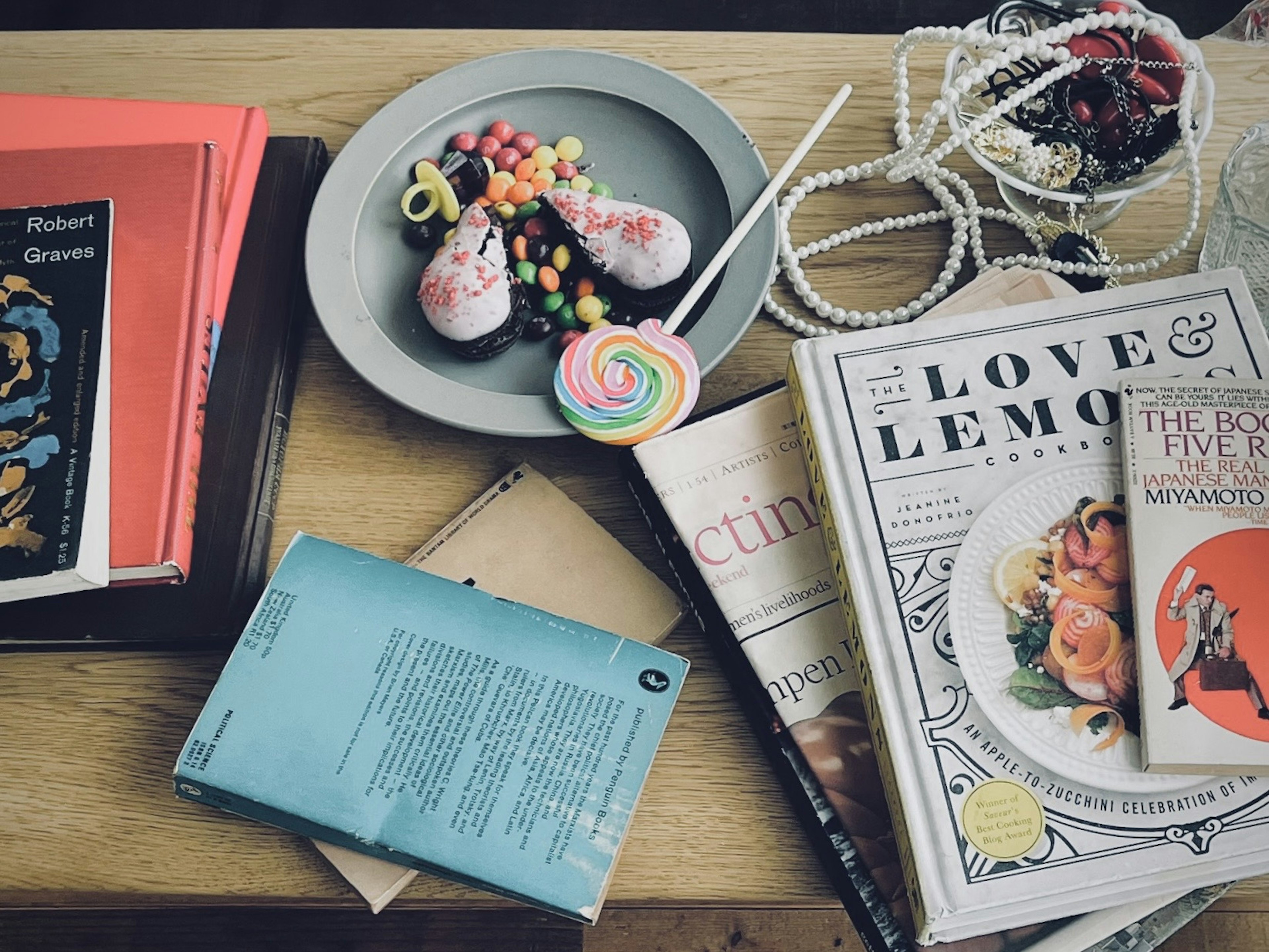 Un piatto di dessert guarnito con caramelle colorate al centro circondato da vari libri e riviste