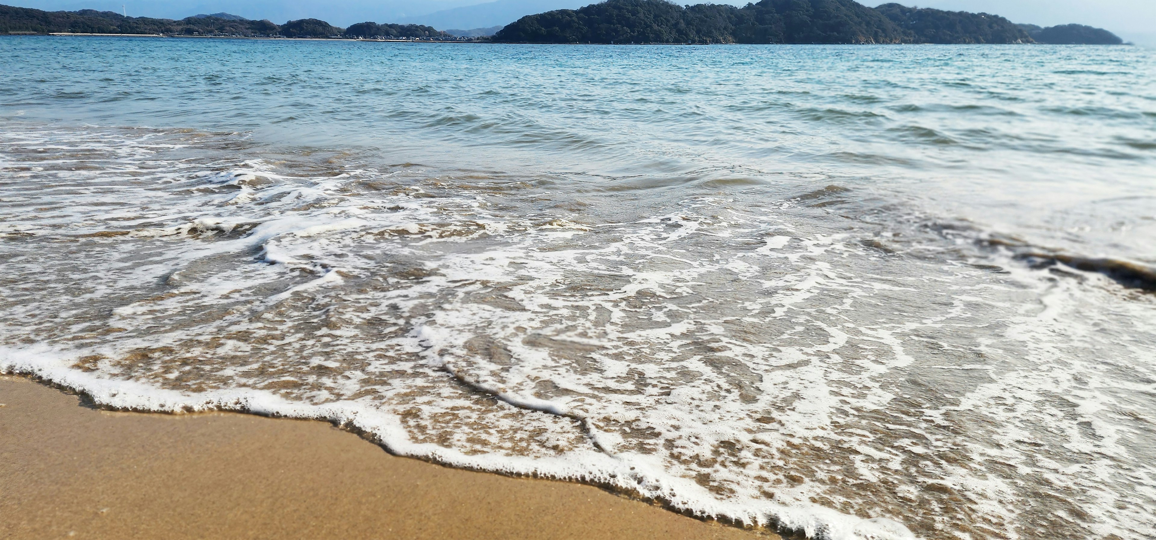 Vista panoramica di una spiaggia sabbiosa con onde oceaniche blu