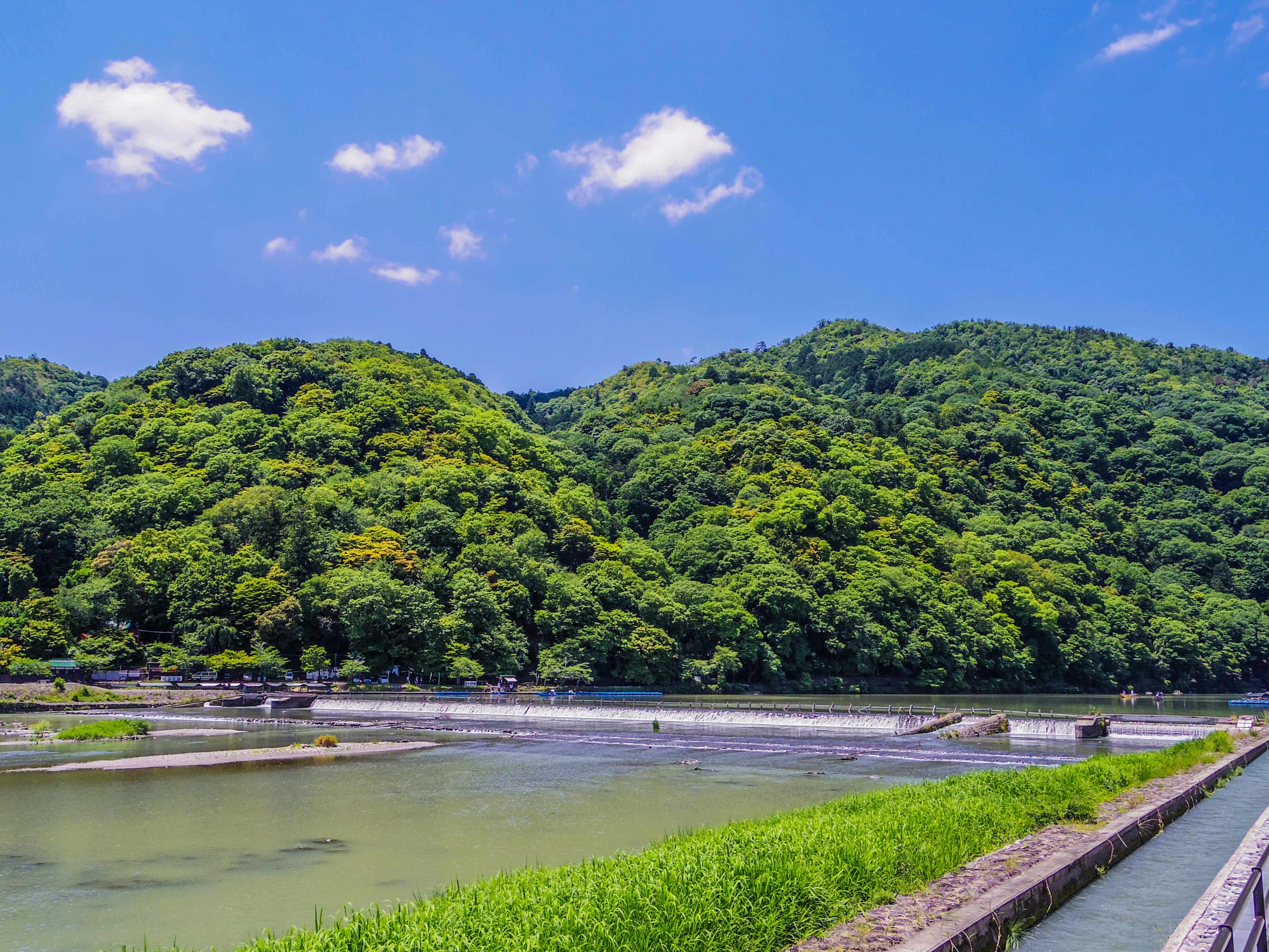 Montagne verdeggianti e paesaggio di fiume sereno sotto un cielo azzurro chiaro