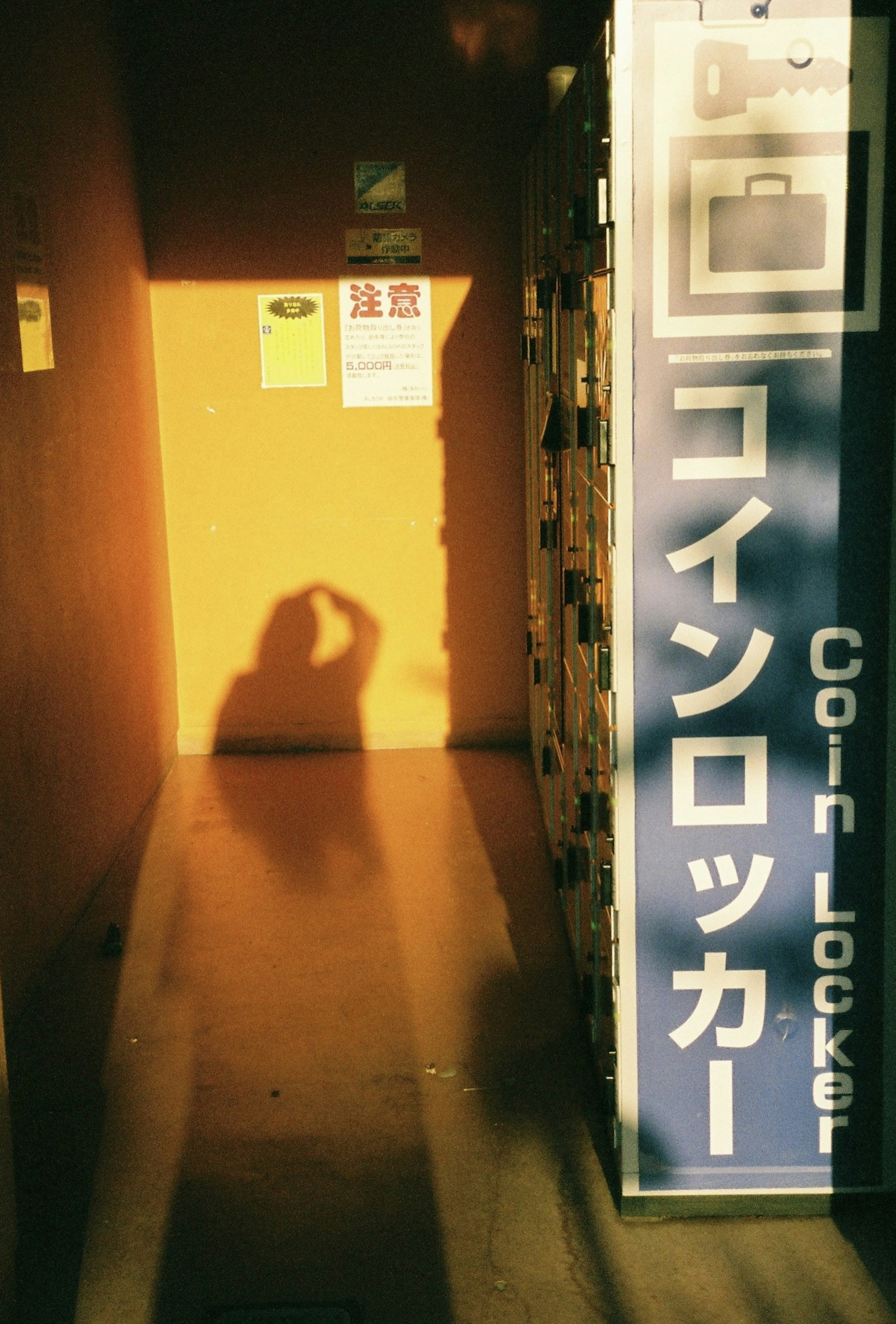 Shadow of a person in front of a coin locker with warm lighting