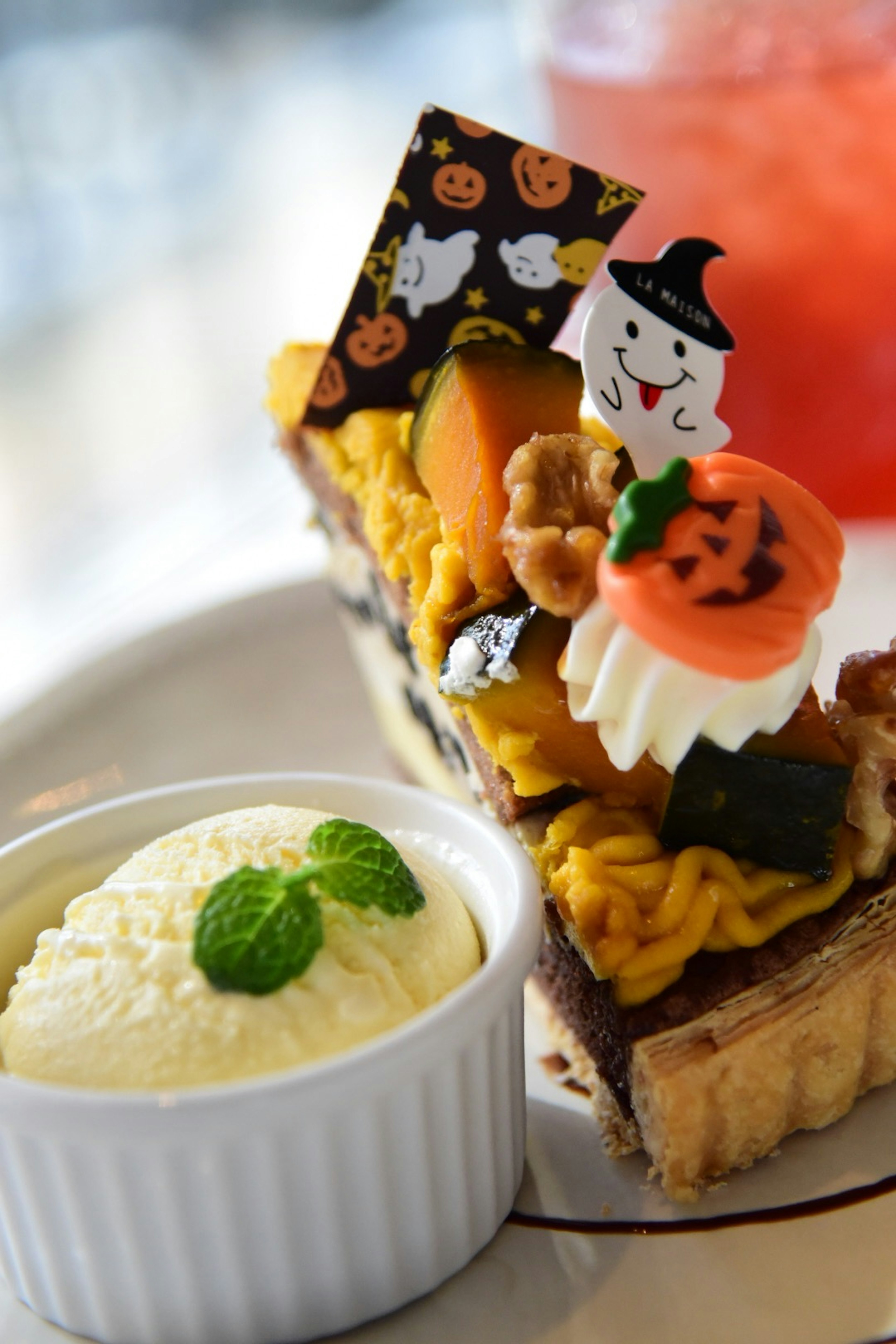 Halloween themed cake slice with ghost and pumpkin decorations alongside vanilla ice cream