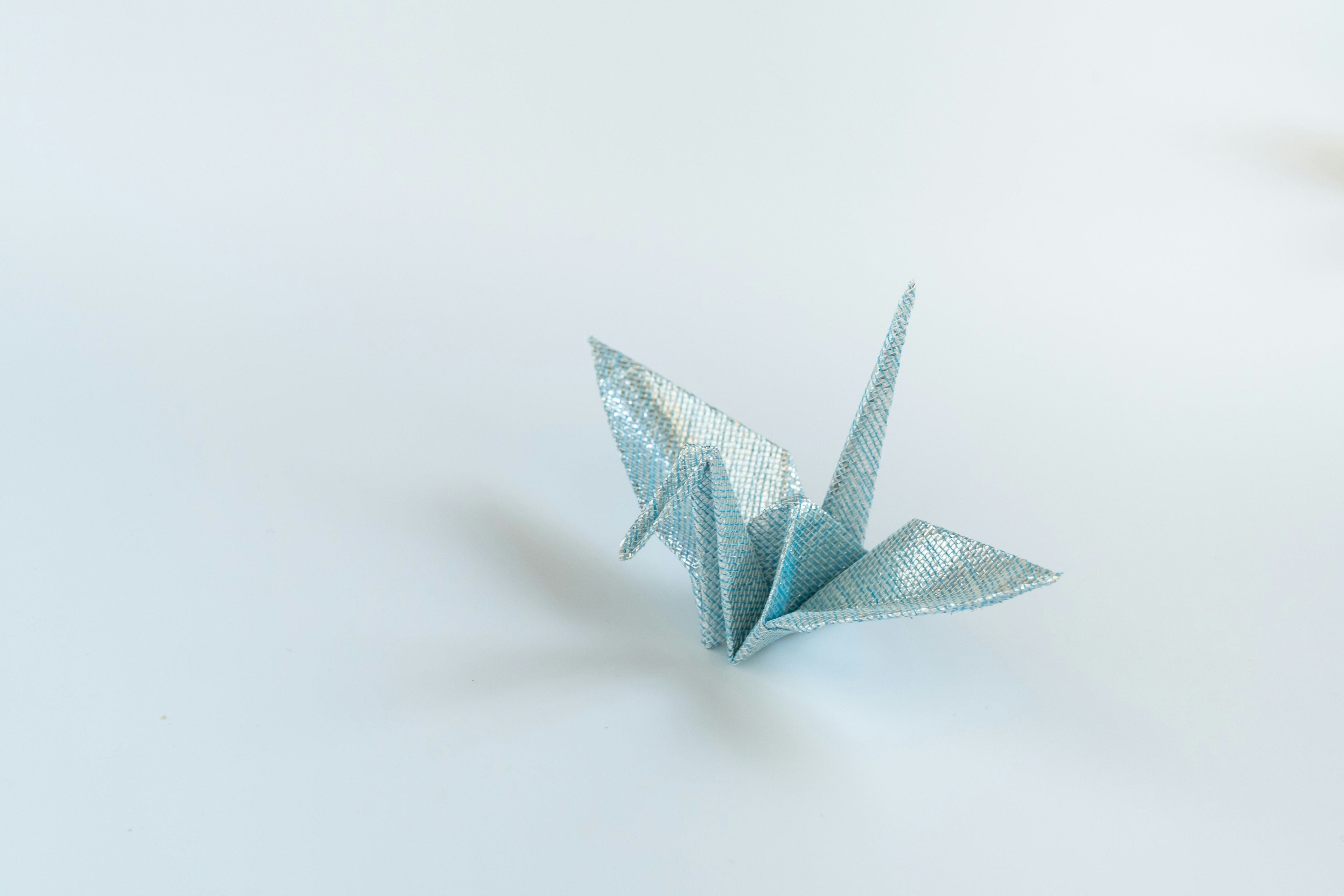 A blue origami crane placed on a white background