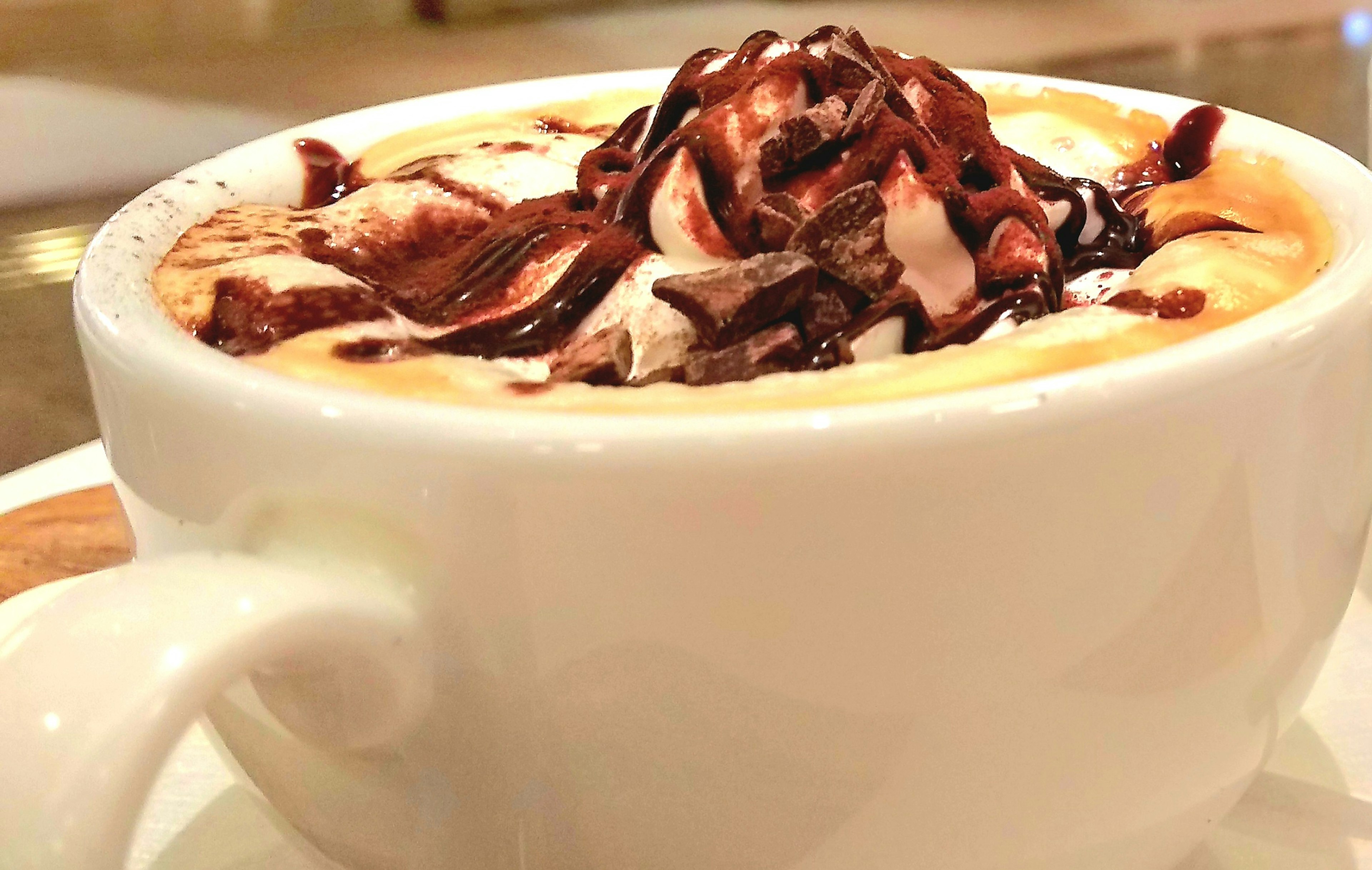 Coffee topped with creamy whipped cream and chocolate sauce