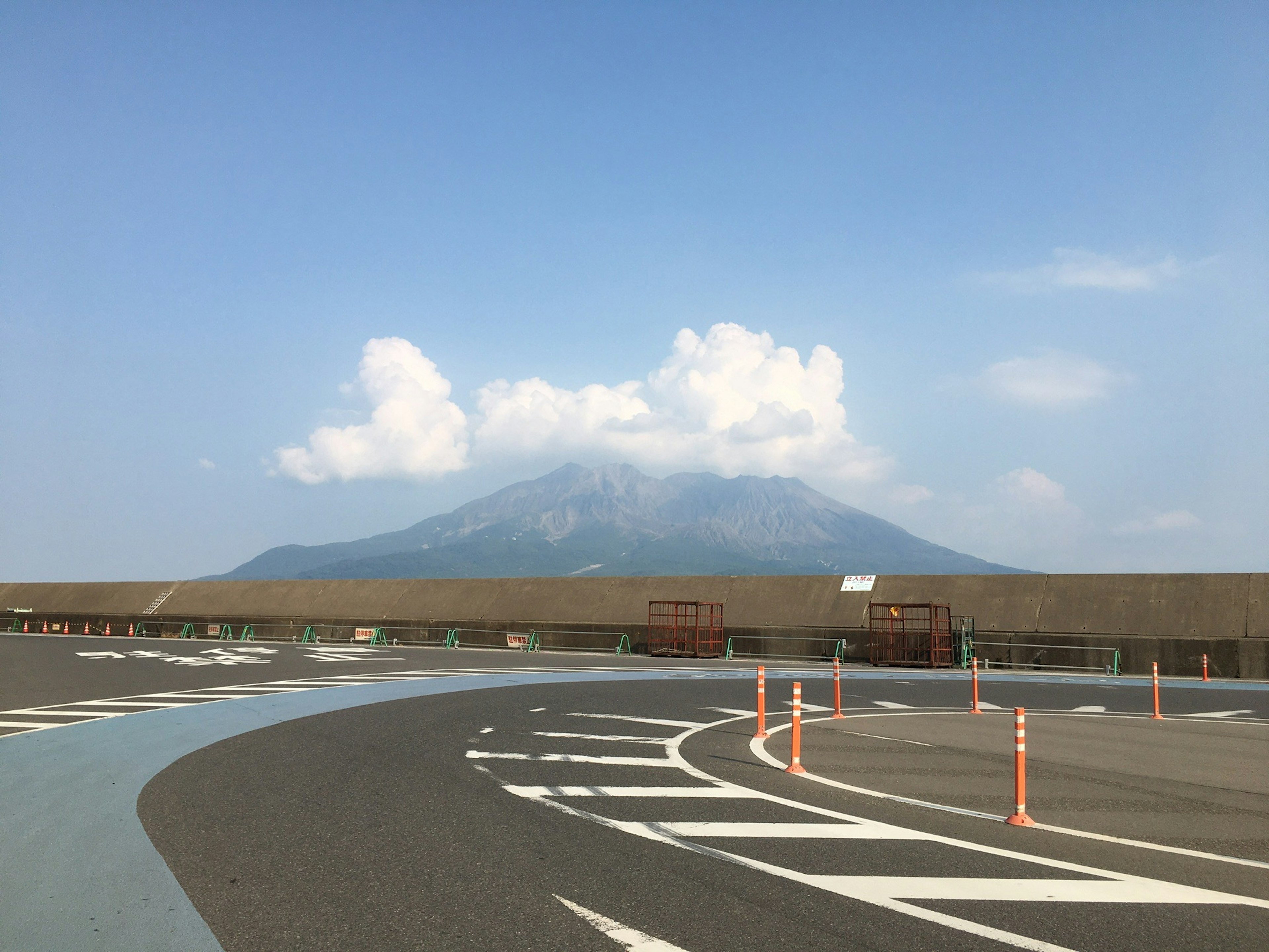 Curved road leading towards a mountain under a blue sky