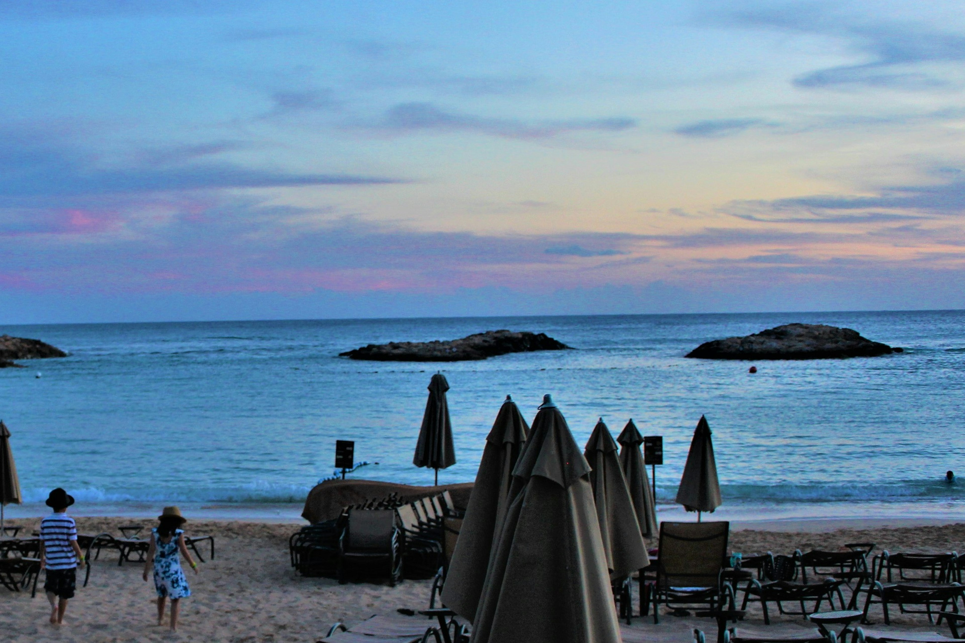 Escena de playa con sombrillas y sillas al atardecer sobre el océano