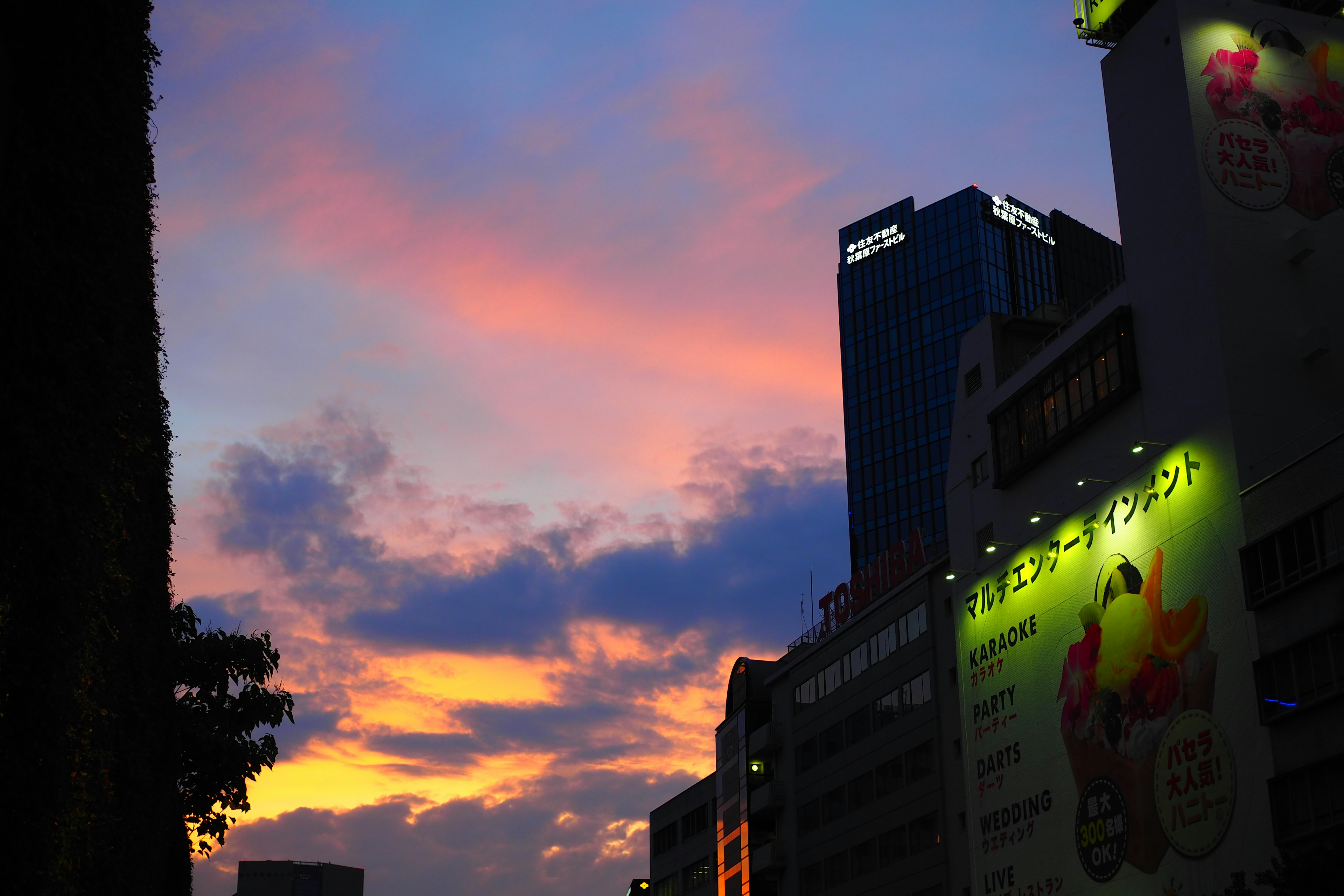 ทิวทัศน์เมืองที่มีท้องฟ้าตอนพระอาทิตย์ตกที่สดใสและตึกระฟ้าที่เป็นเงา