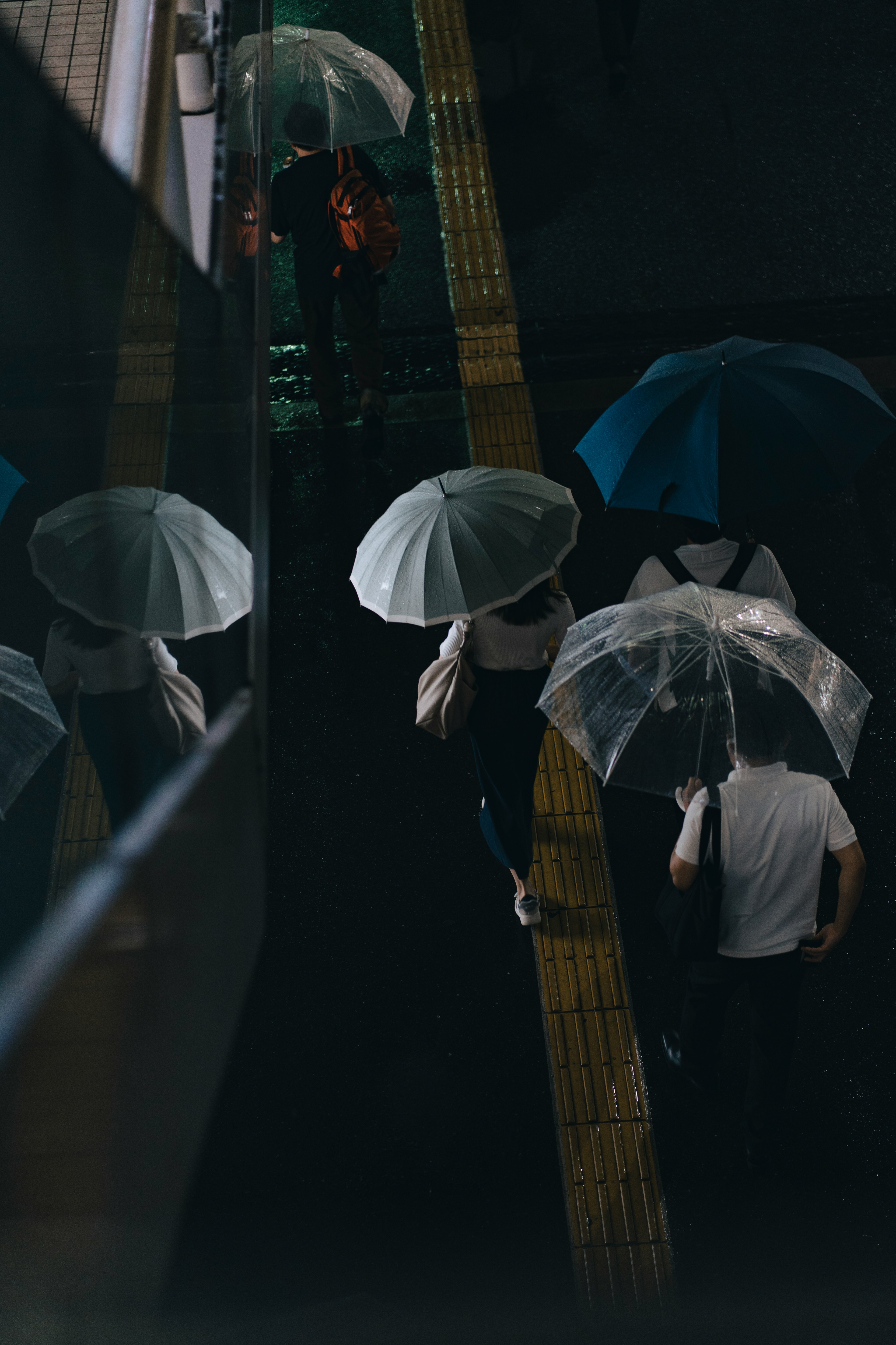 雨の中で傘を持った人々が歩いている様子