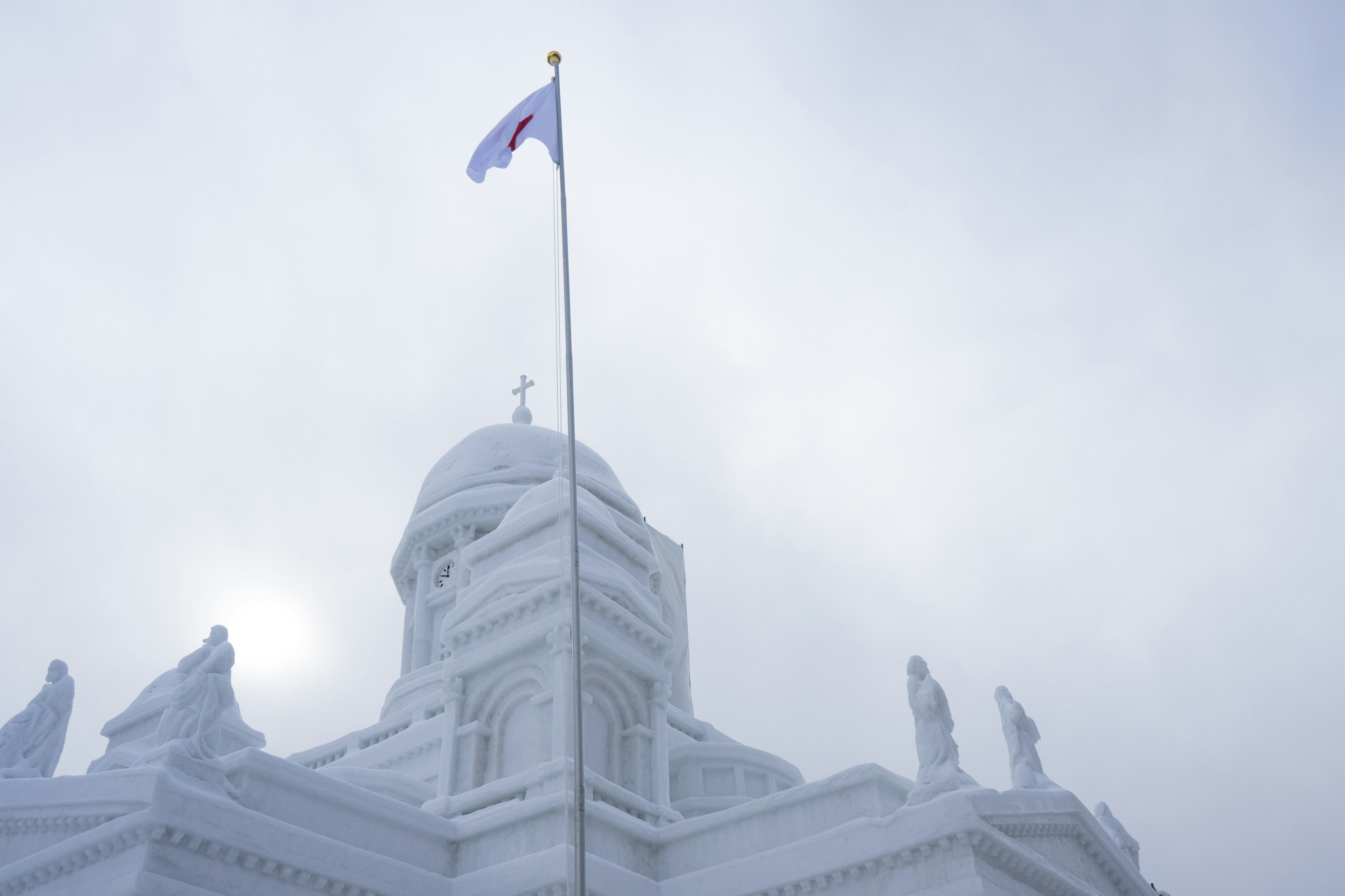 Imagen de una cúpula de edificio cubierta de nieve con una bandera