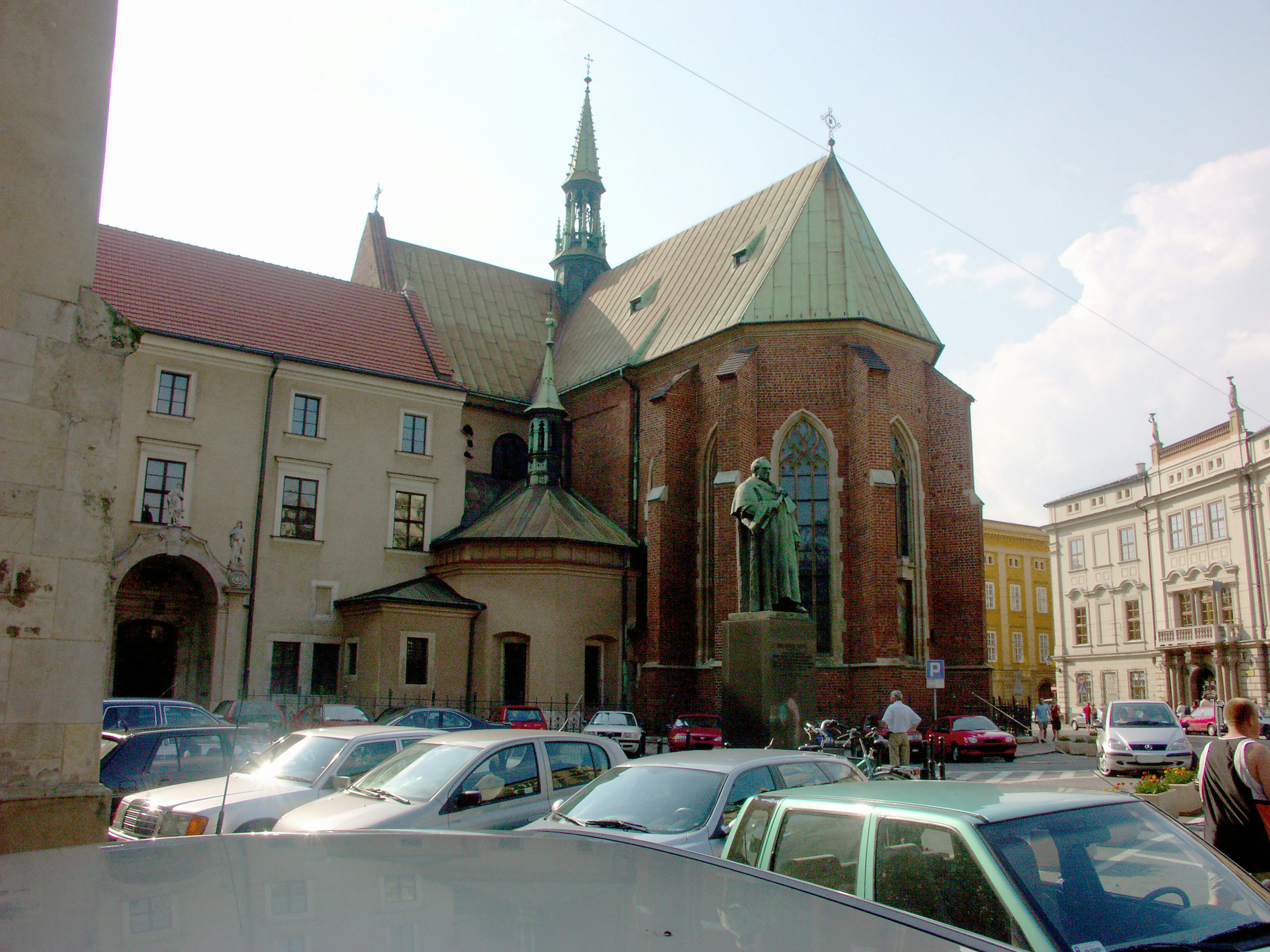 Vista panoramica di una chiesa in mattoni con un tetto verde circondata da auto parcheggiate