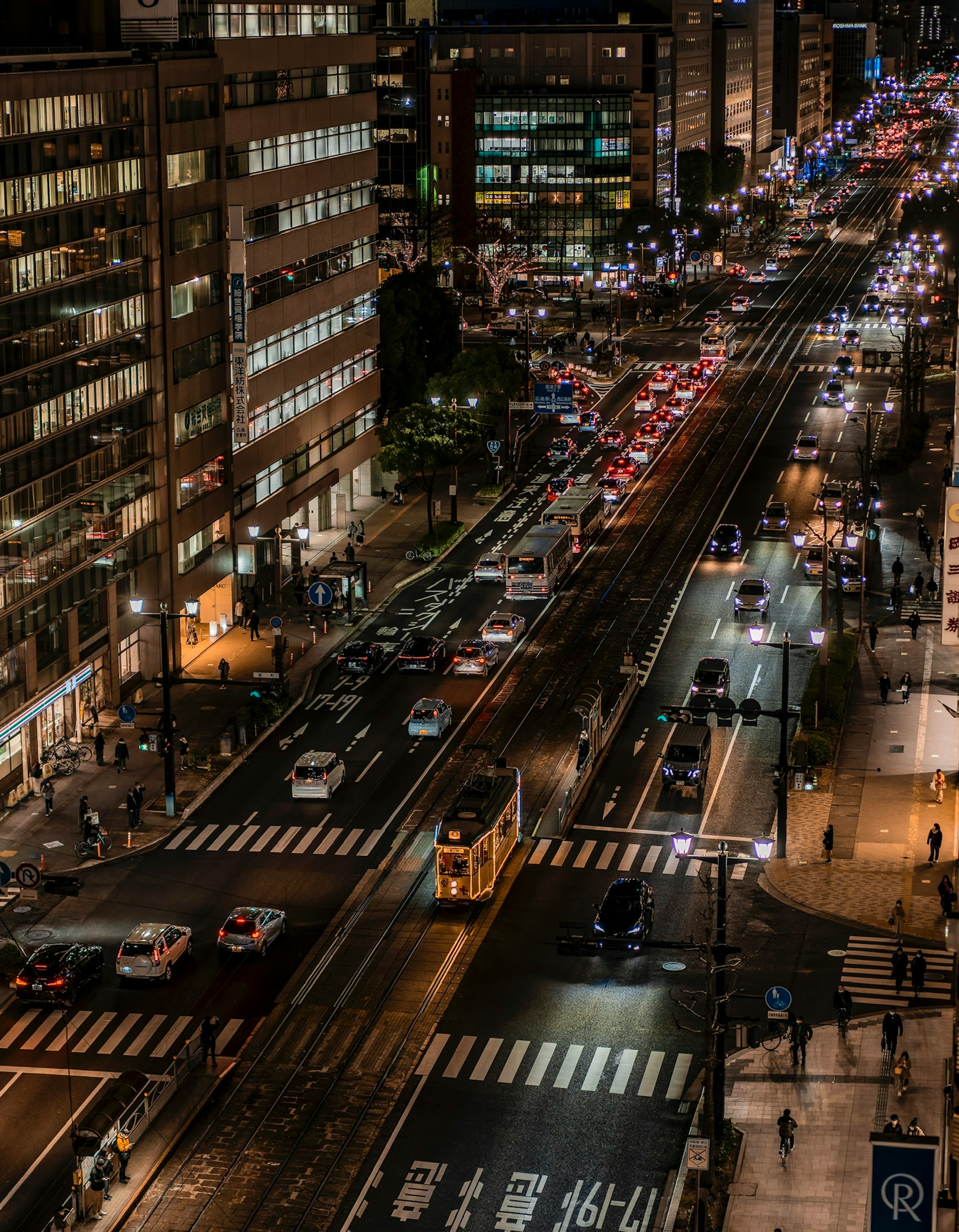 Vue nocturne d'une ville avec circulation animée et bâtiments illuminés