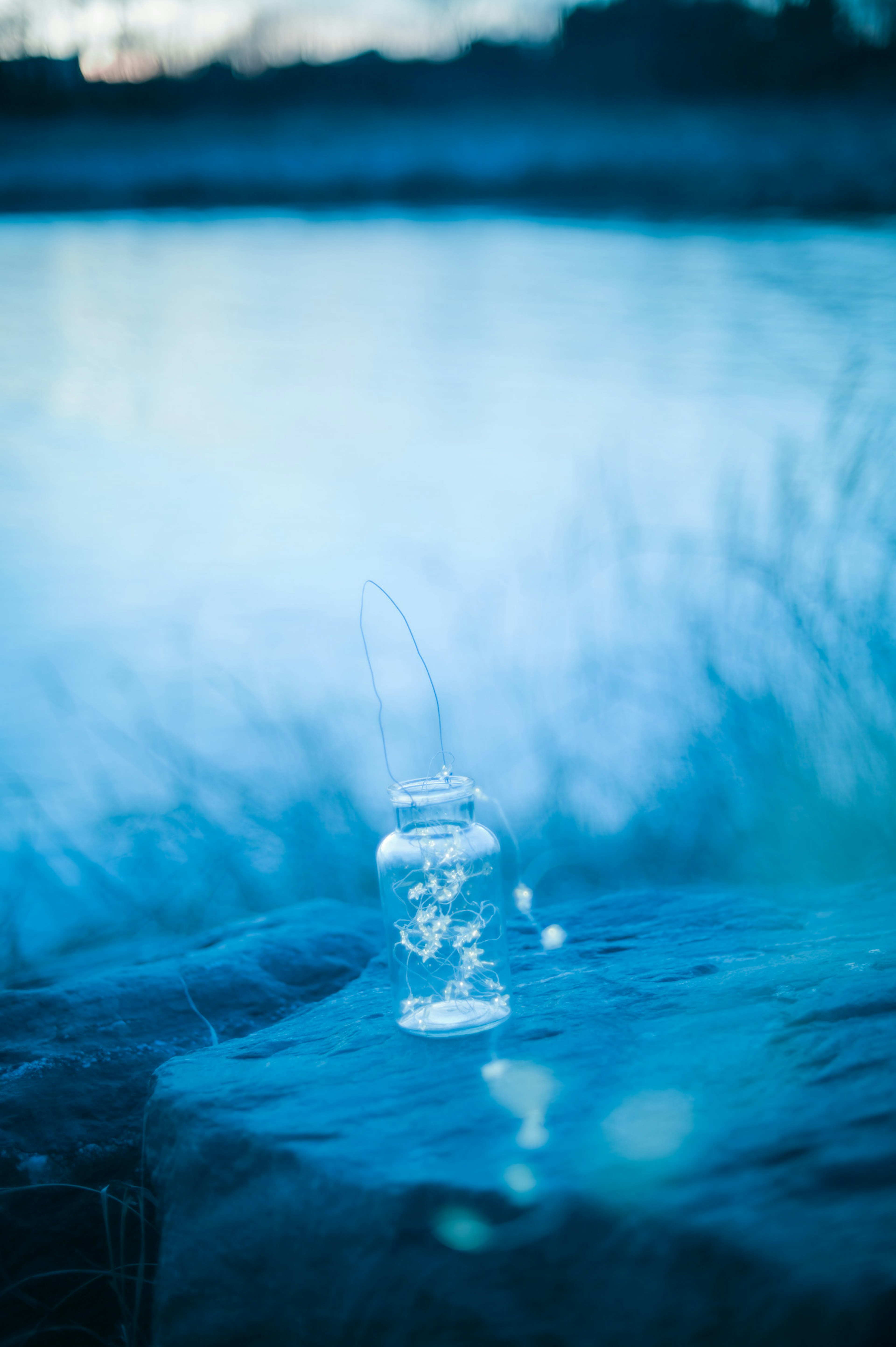 Glasgefäß, das auf einer blauen Oberfläche schwebt, mit verschwommenem Hintergrund