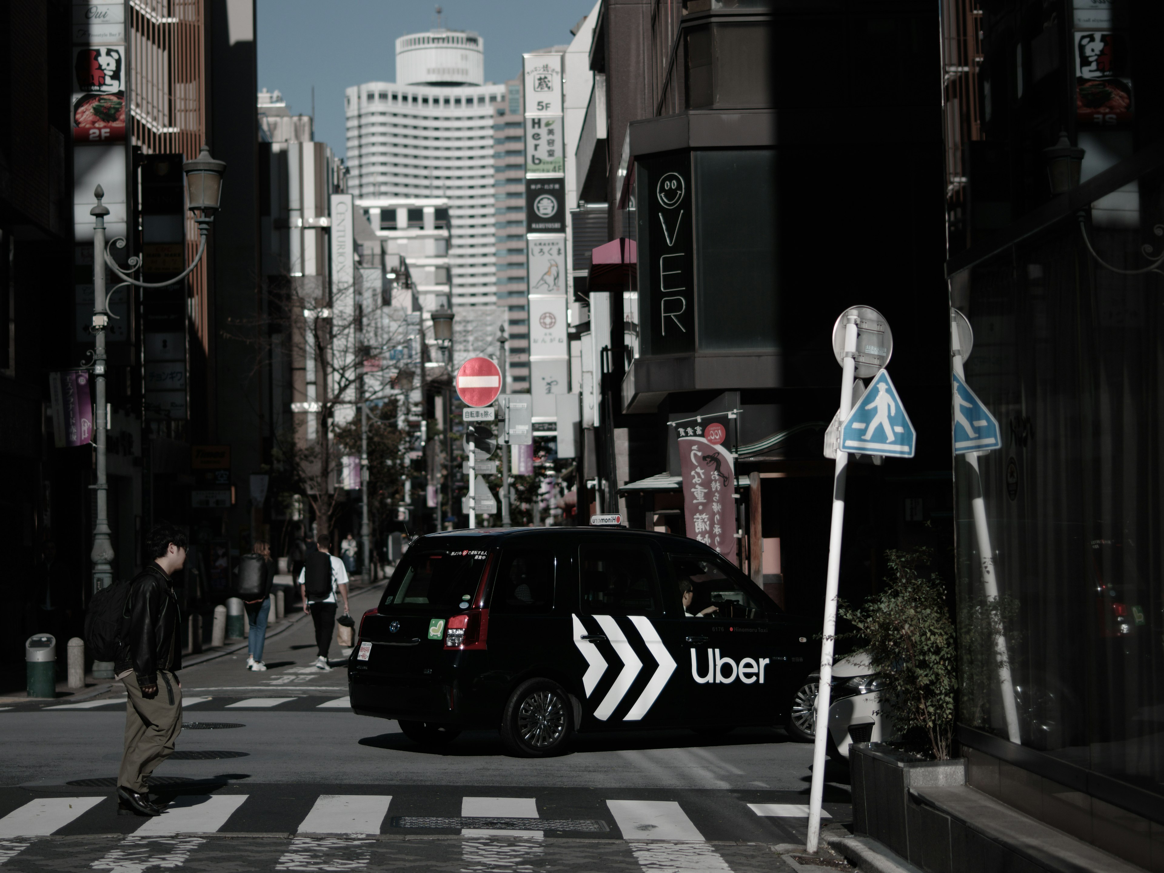 都市の通りを横切るUberの車と街の風景