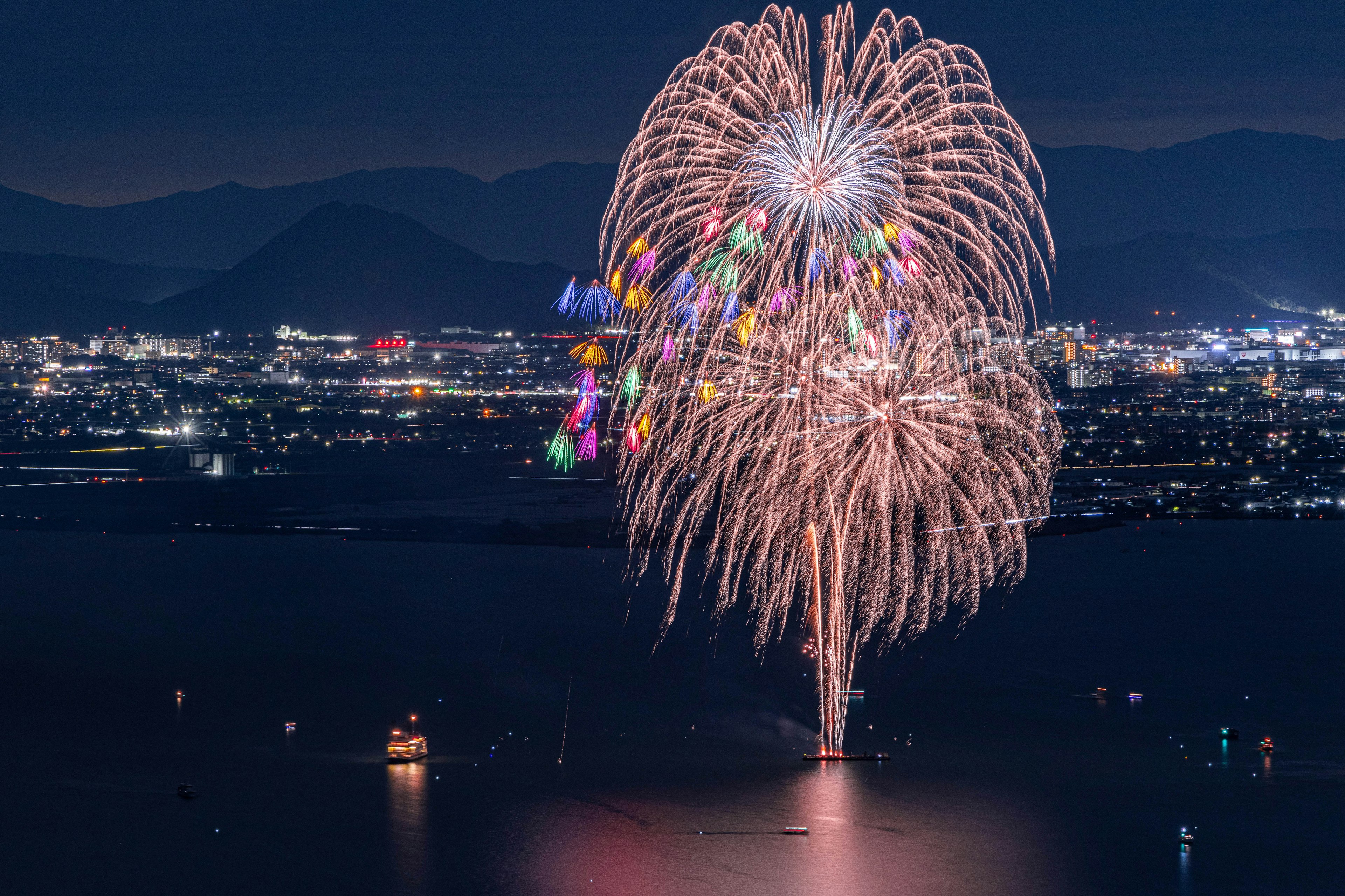 夜空に花火が打ち上げられ都市の光が背景に広がる