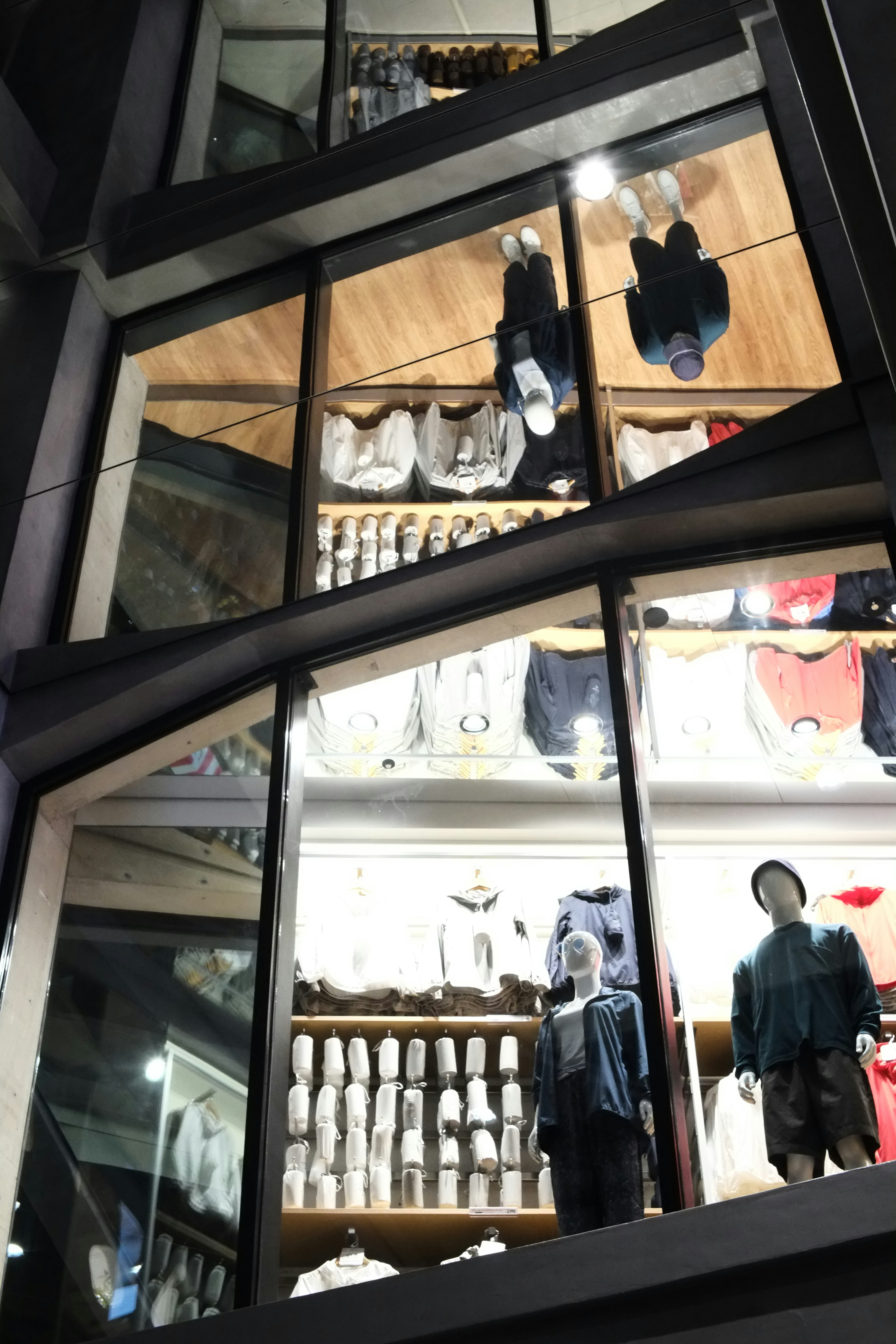 Modern store glass window reflecting clothing and mannequin displays