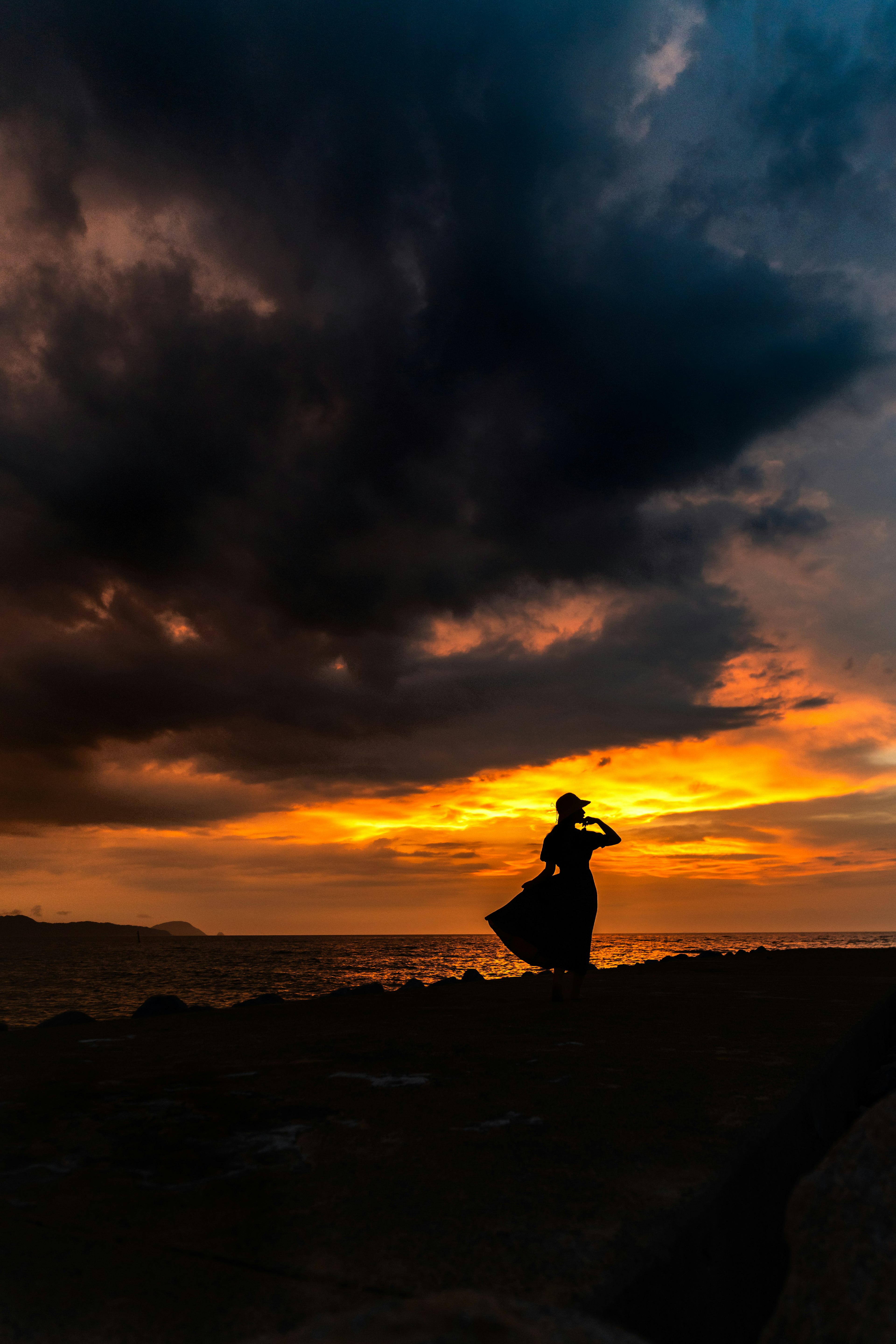 夕焼けの中で踊る女性のシルエットと暗い雲