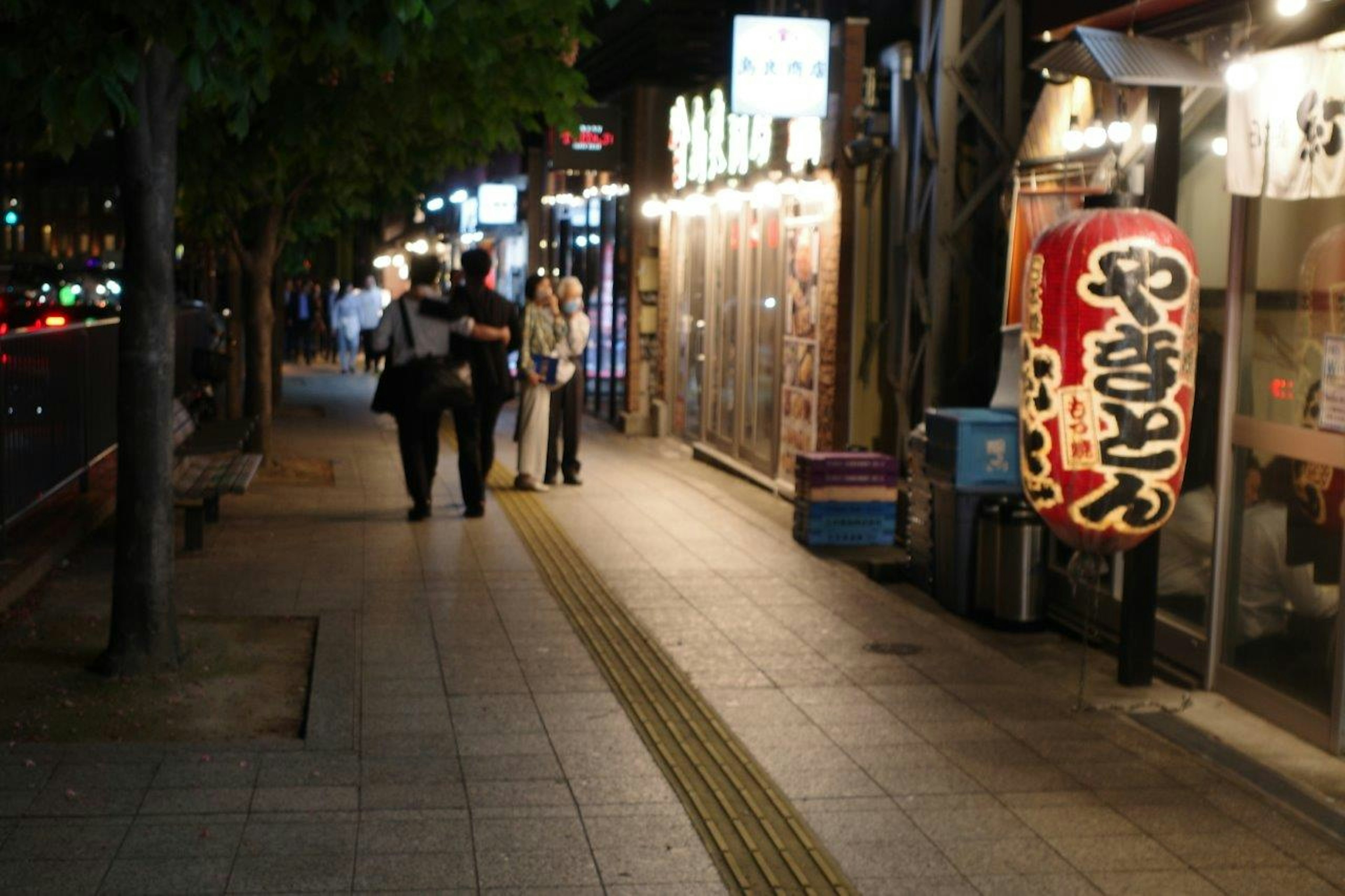 夜の街並みを歩く人々と居酒屋の看板