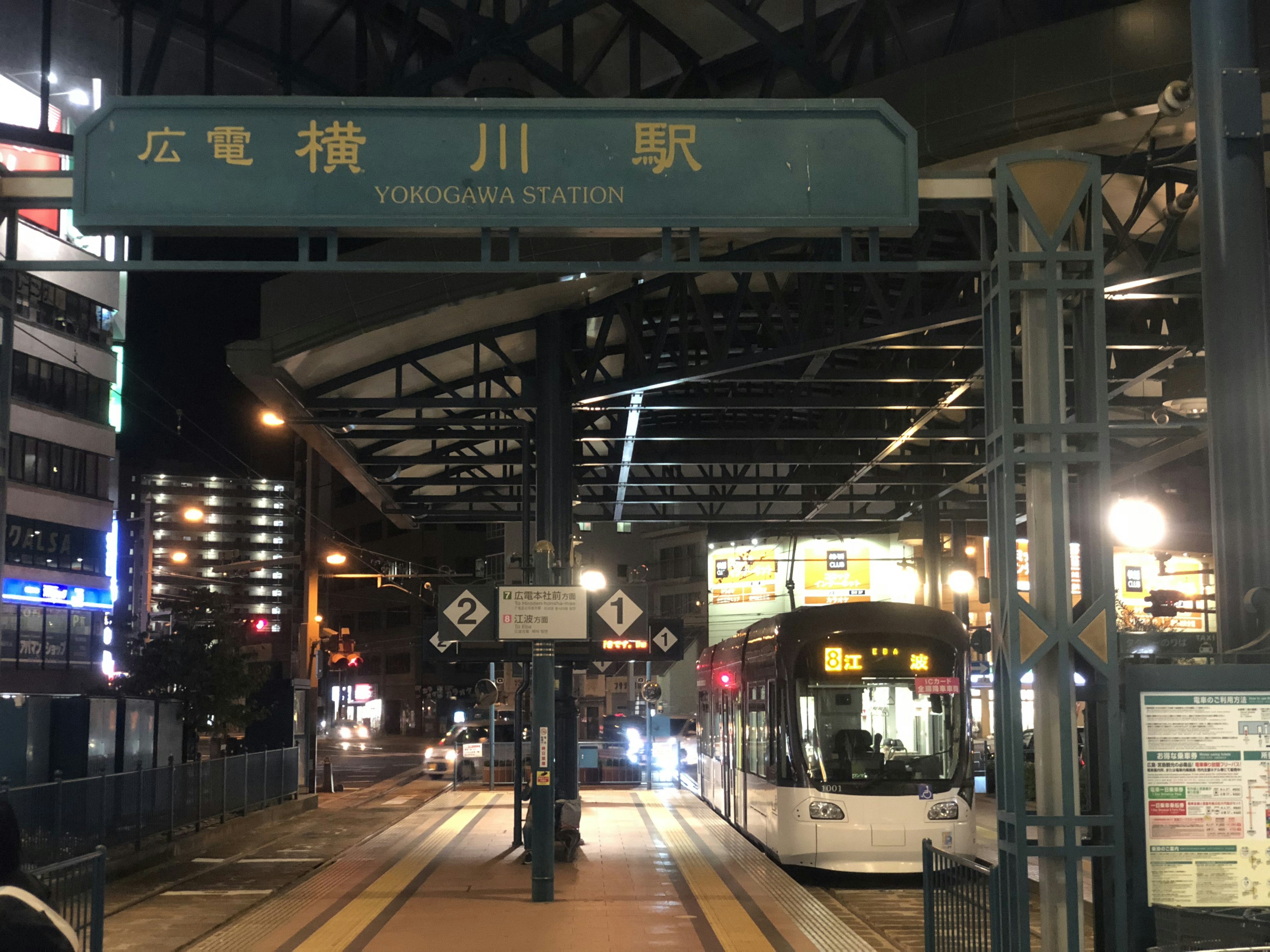 Vista nocturna de la estación Hiroden Yokogawa con tranvía