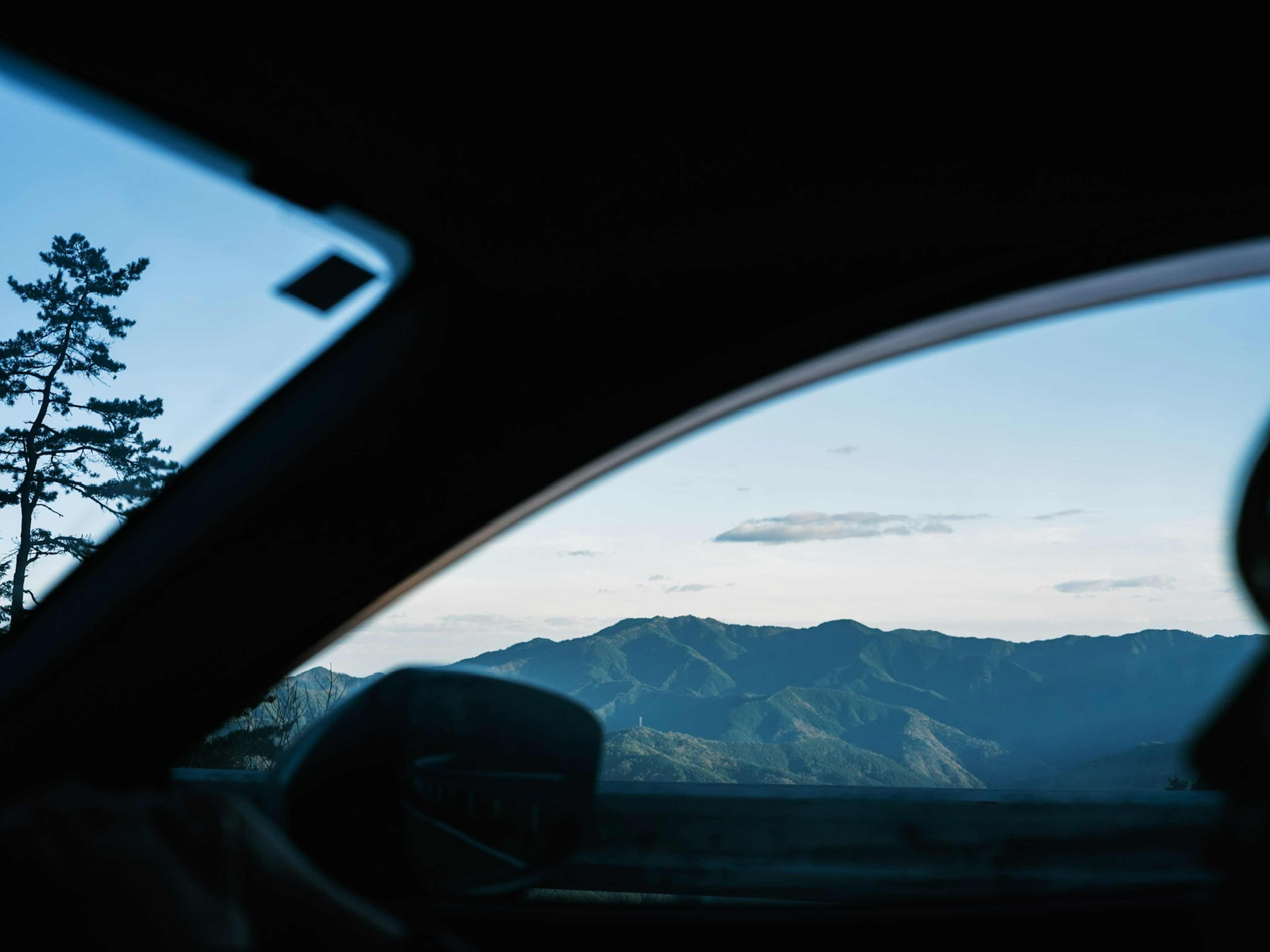 Pemandangan pegunungan dan langit biru terlihat melalui jendela mobil