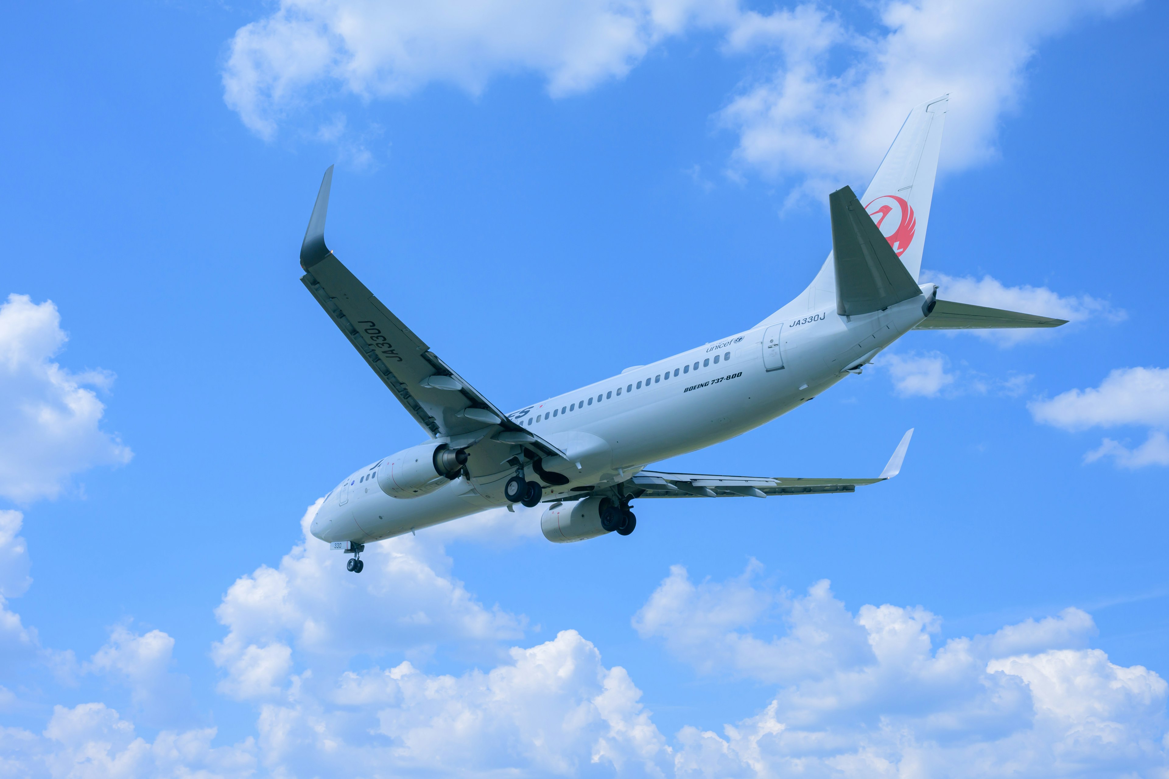 Flugzeug fliegt gegen einen blauen Himmel mit Wolken